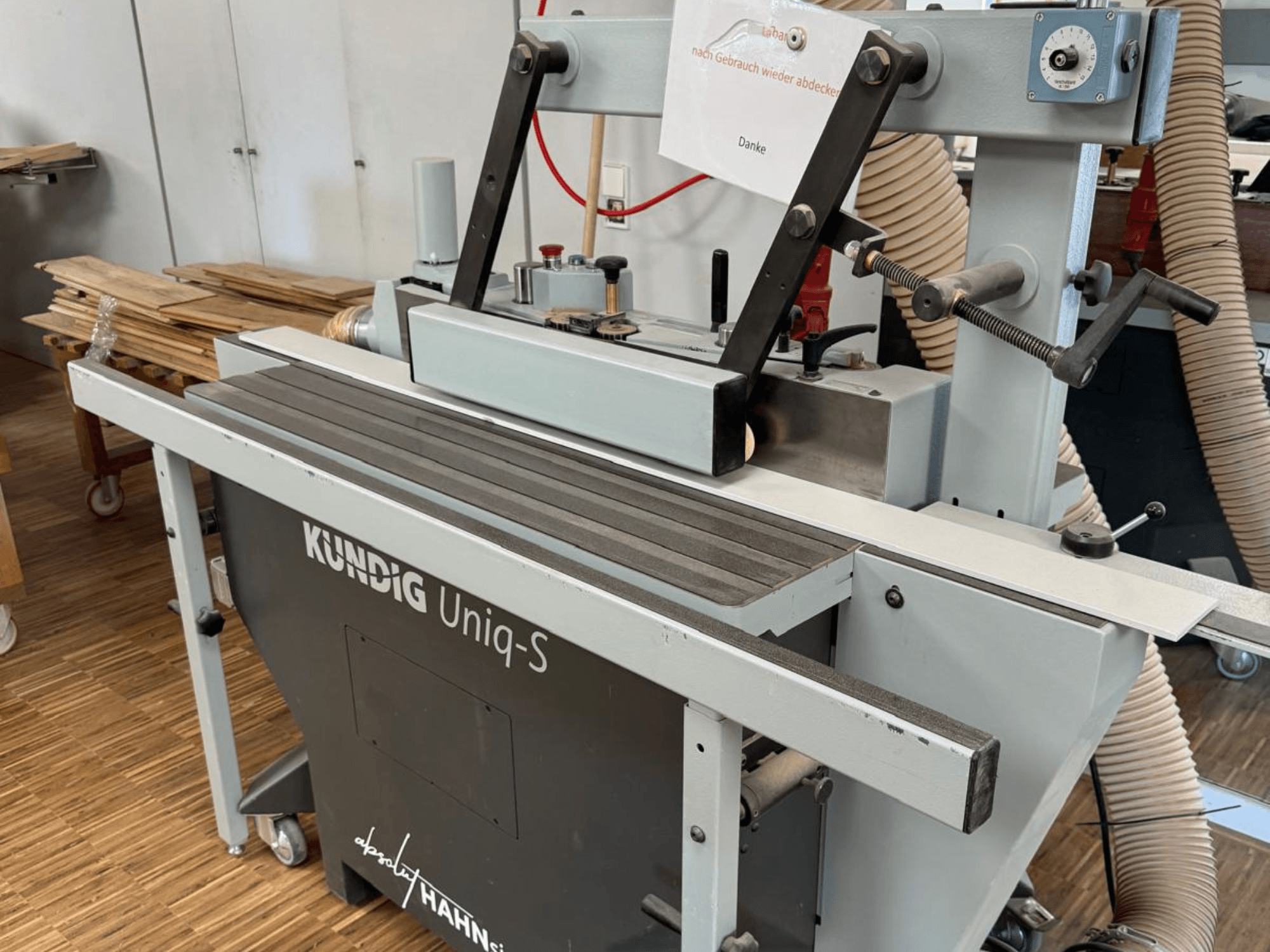 Kundig UNIQ-S szalagcsiszoló egy műhelyben, oldalnézetben a csiszolószalag és az állítható támasztókarok.