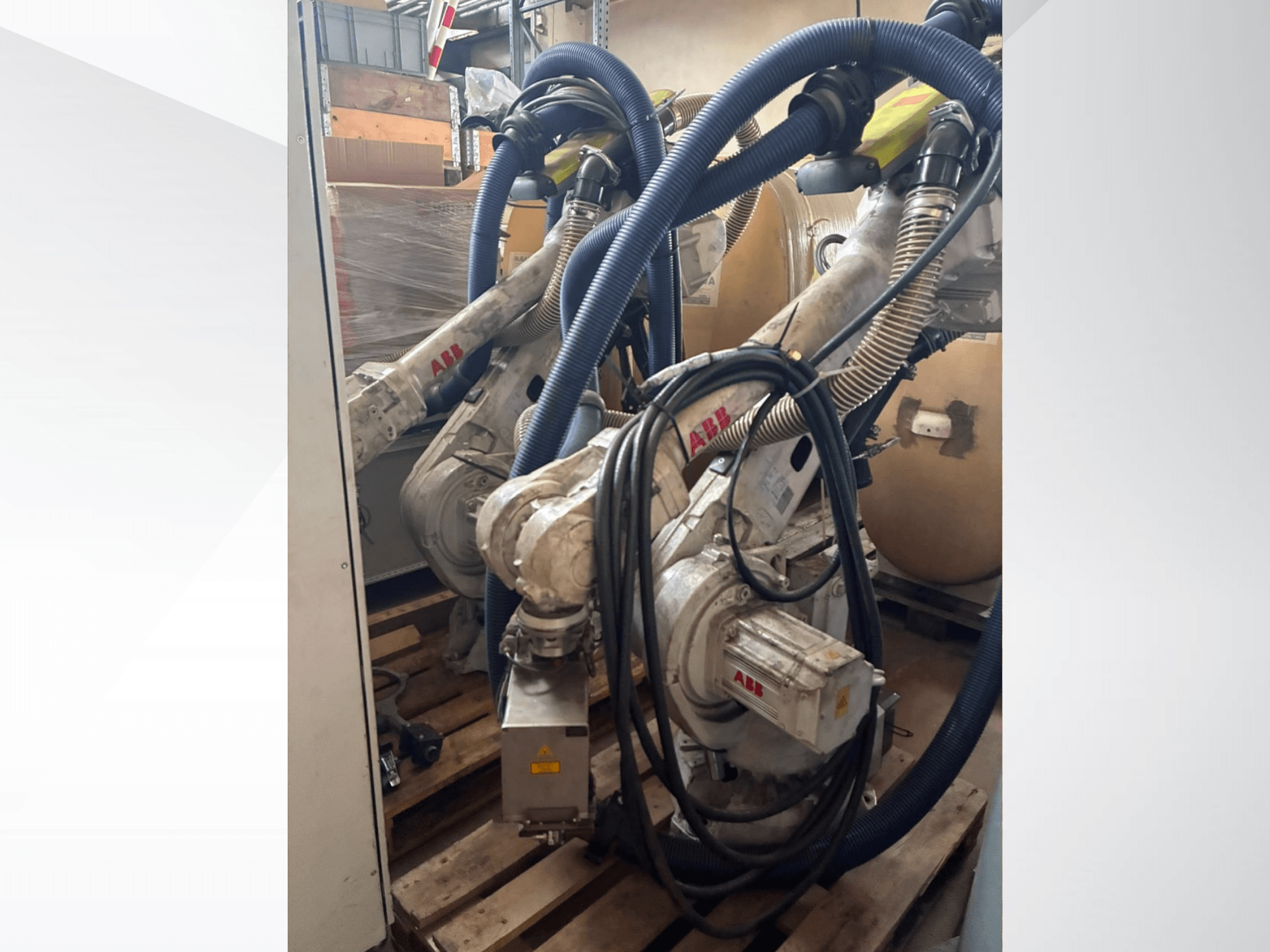 ABB IRB 4600-40/2,55 robotkar, oldalnézet, amelyen láthatók a két kar és a hozzájuk csatlakozó tömlők; a robotkarok raktári környezetben raklapokra vannak felszerelve.