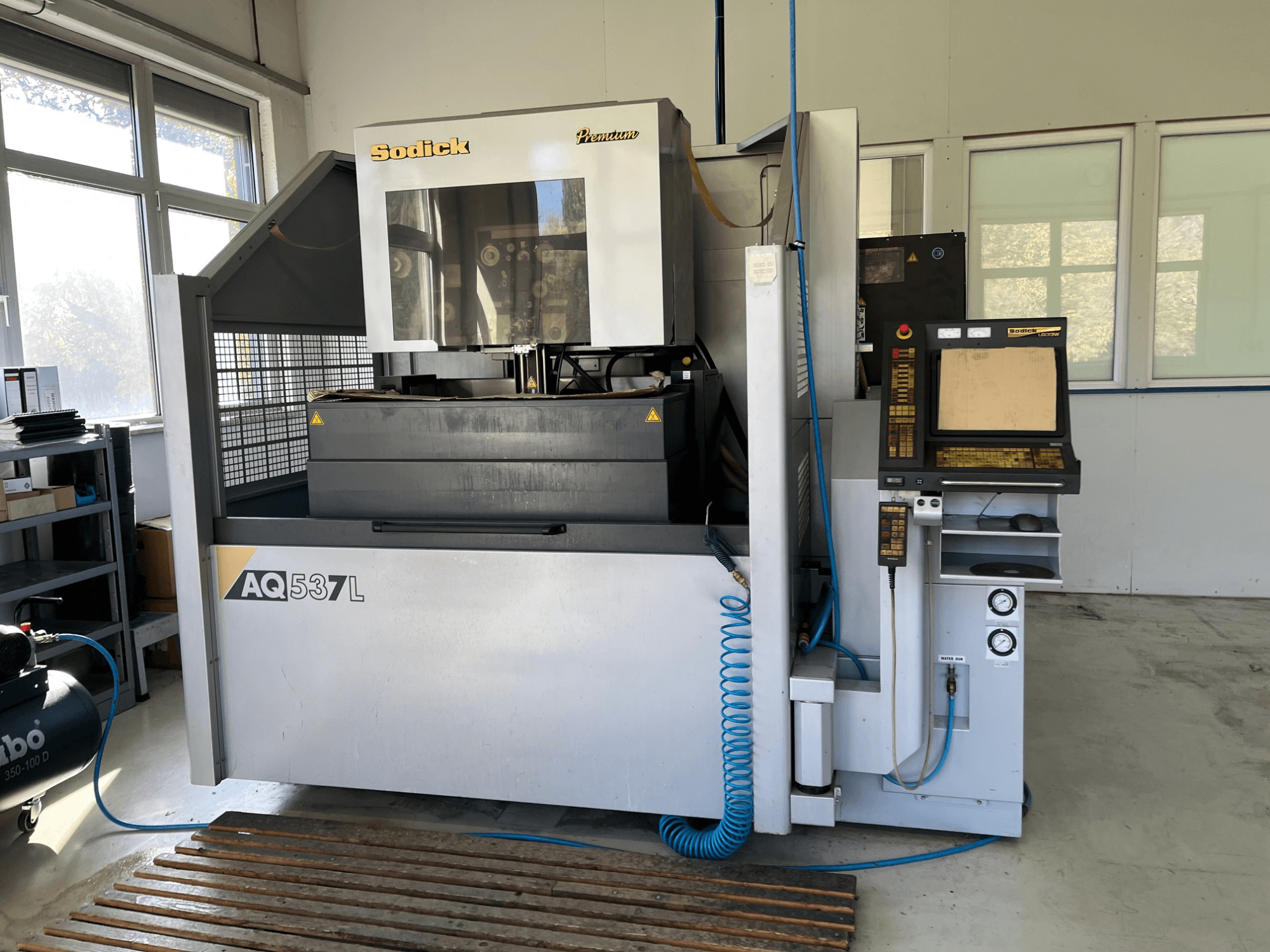 Sodick AQ537L elektromos kisüléses gép (EDM) elölnézetben, a vezérlőpanel, a vízhűtő vezetékek és a munkaterület.