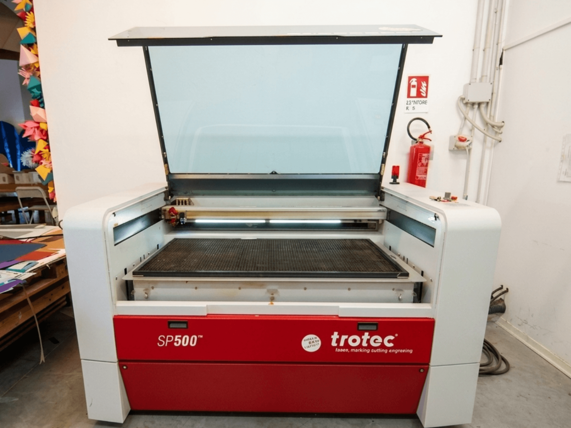 Trotec SP500 C200 lézergravírozó gép elölnézetben, nyitott fedéllel, amelyen a munkaterület és a kezelőszervek láthatók.