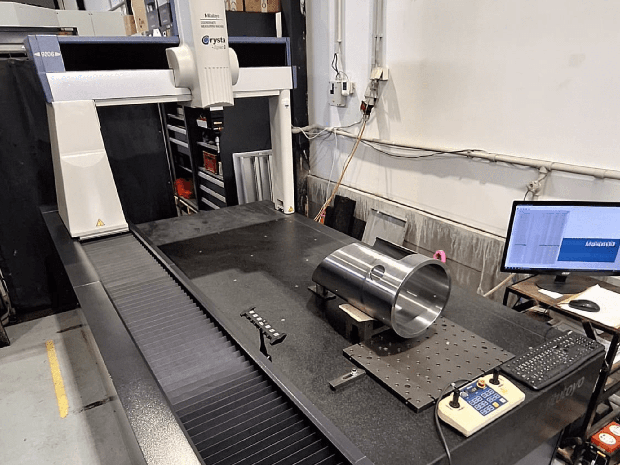 Mitutoyo Crysta-Apex C9206 CMM elölnézetben, egy hengeres fém alkatrész mérése egy fekete gránit felületű lemezen.