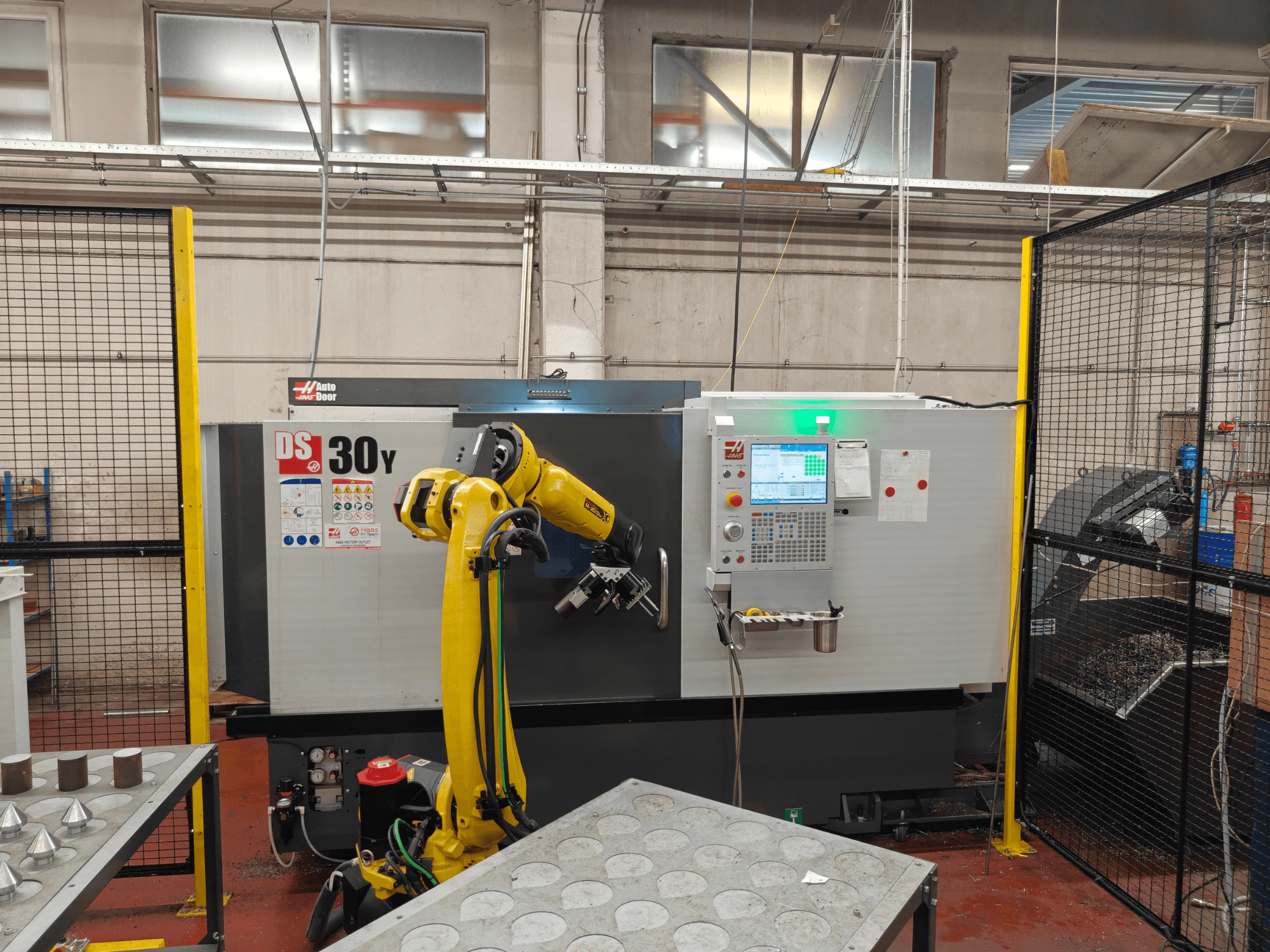 HAAS DS30Y vízszintes eszterga robotkarral, elölnézetből, a vezérlőpanellel és a munkaterülettel.