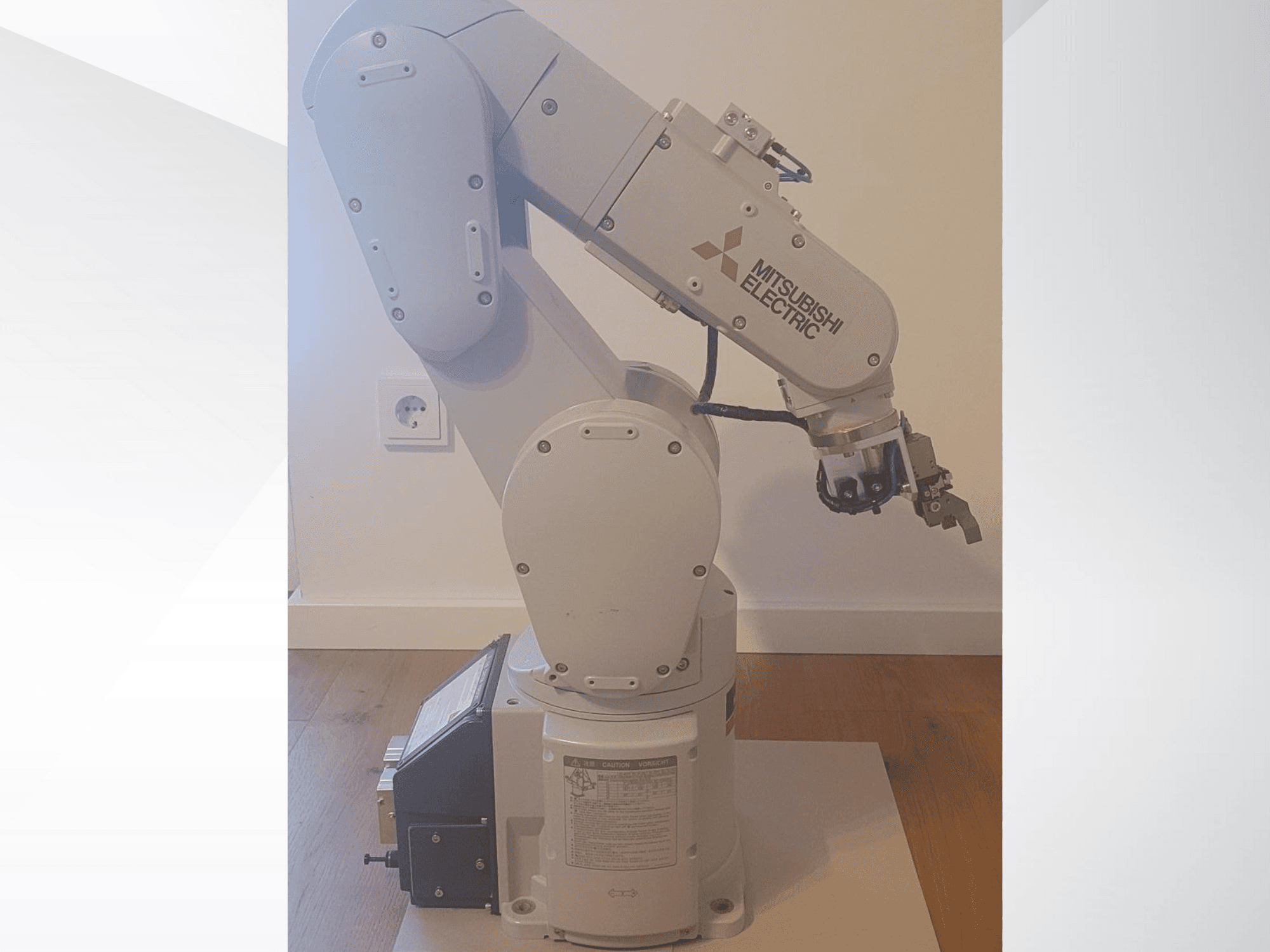 Mitsubishi Electric robotkar, oldalnézet, markolóval és részletes vezérlőpanellel az alapon a működési beállításokhoz.