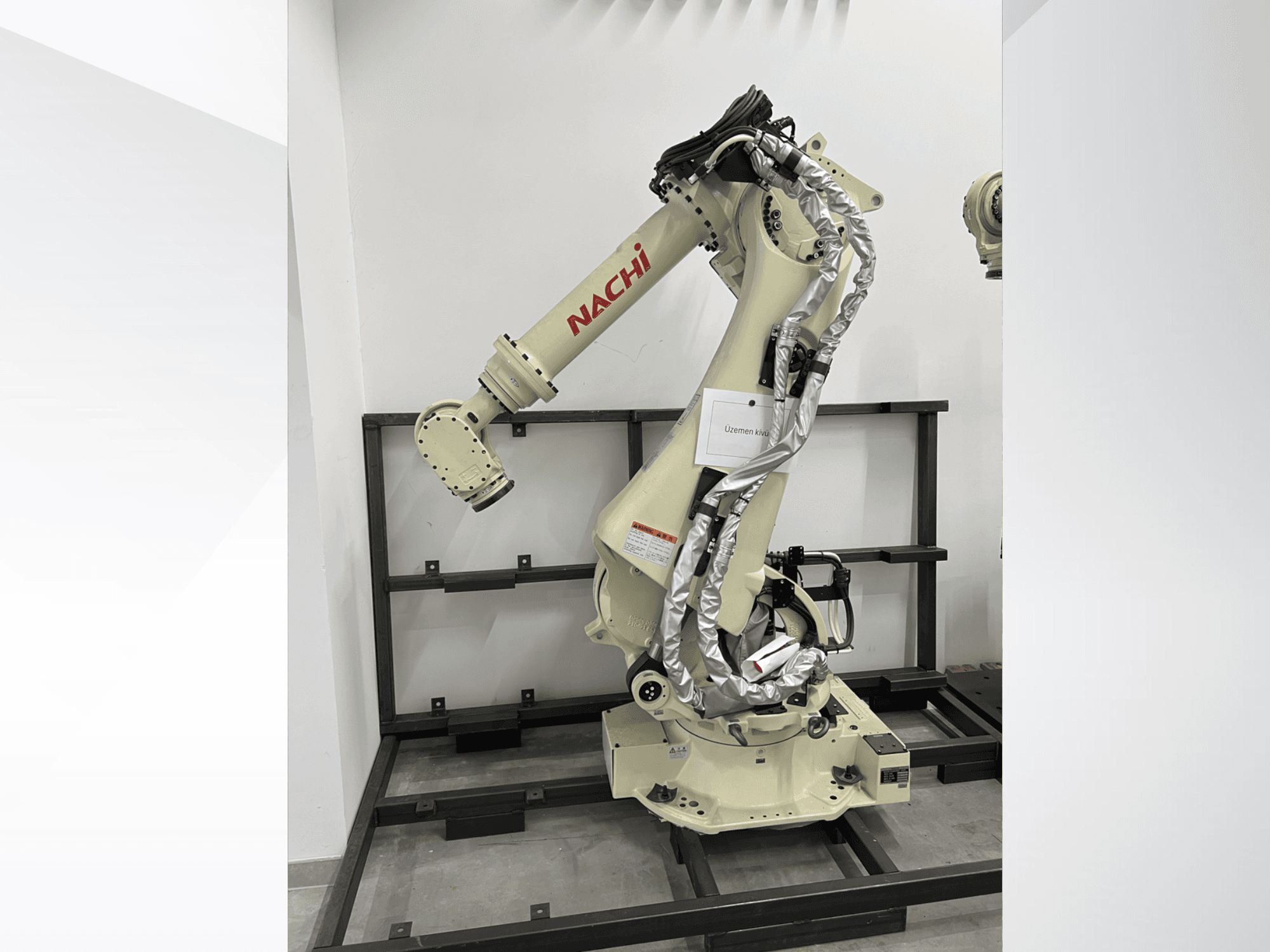 NACHI SRA166-01 robotkar oldalnézetben, rugalmas ízületekkel, csatlakoztatott kábelekkel és védőkeretre szerelve.