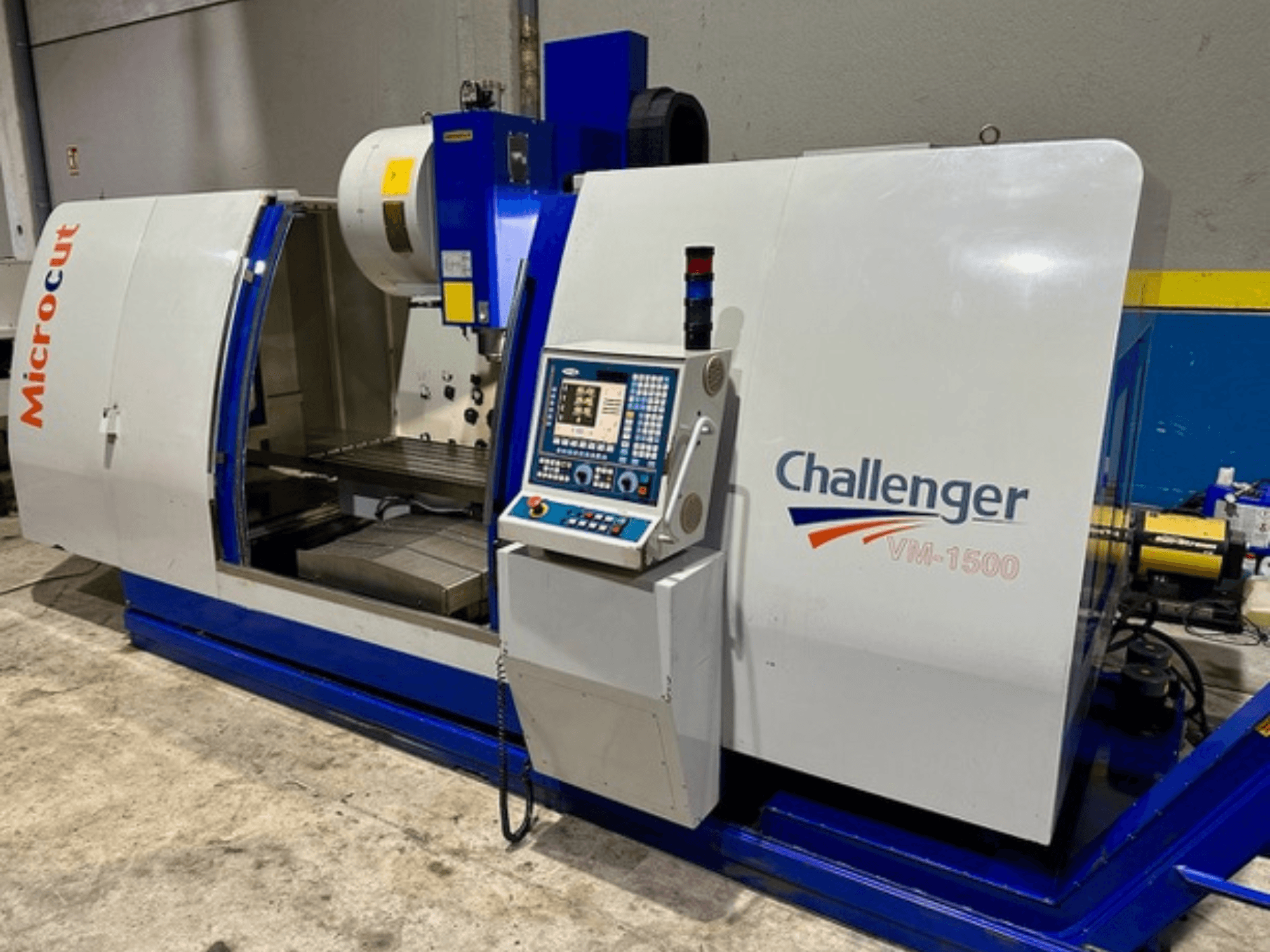 Microcut Challenger VM-1500 CNC gép, előlnézet, vezérlőpanel, munkaterület és kék alap.