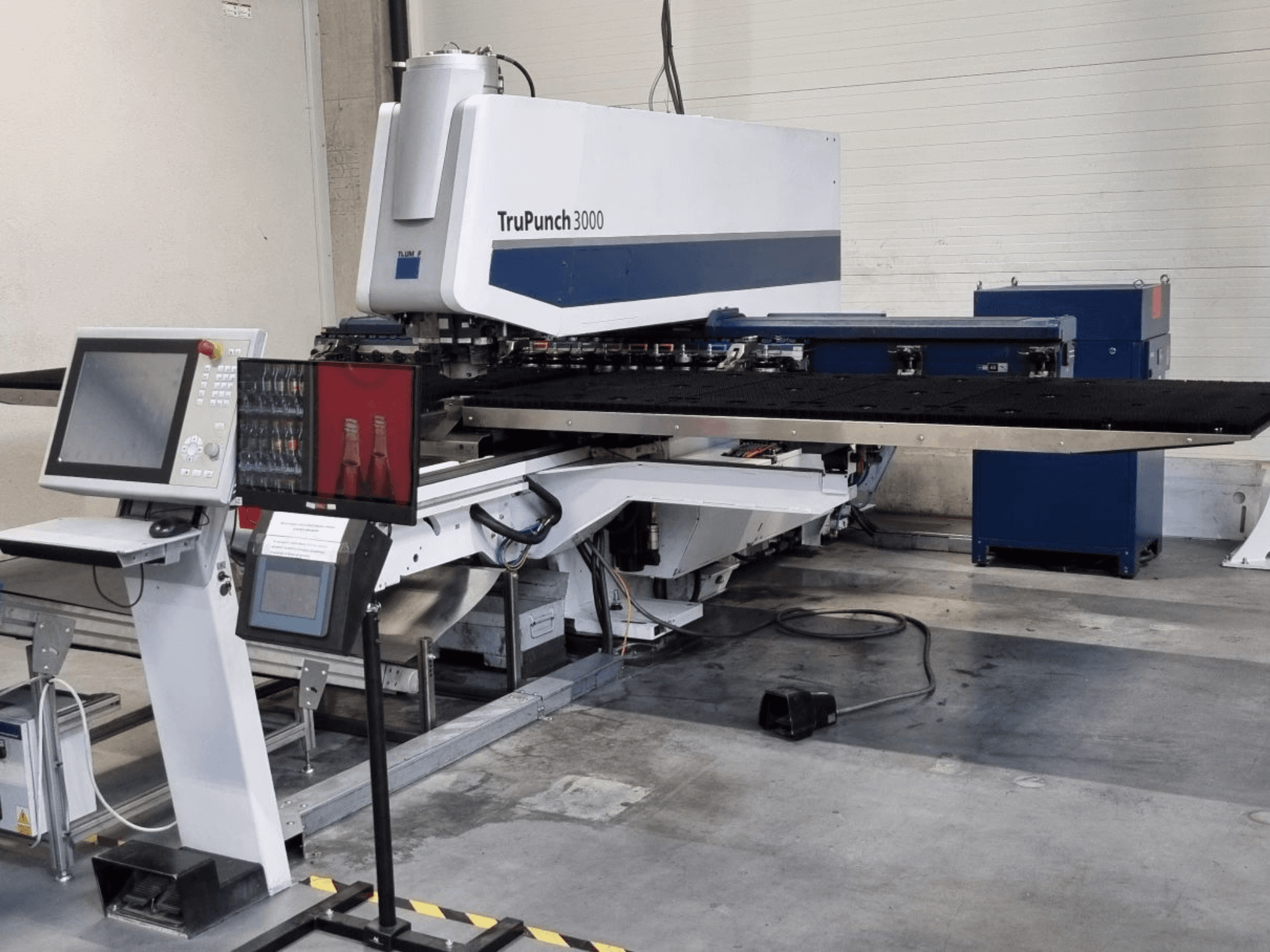 A TRUMPF TruPunch 3000 CNC-lyukasztógép elölnézetben, a vezérlőpanellel és a nagy lyukasztóasztallal.