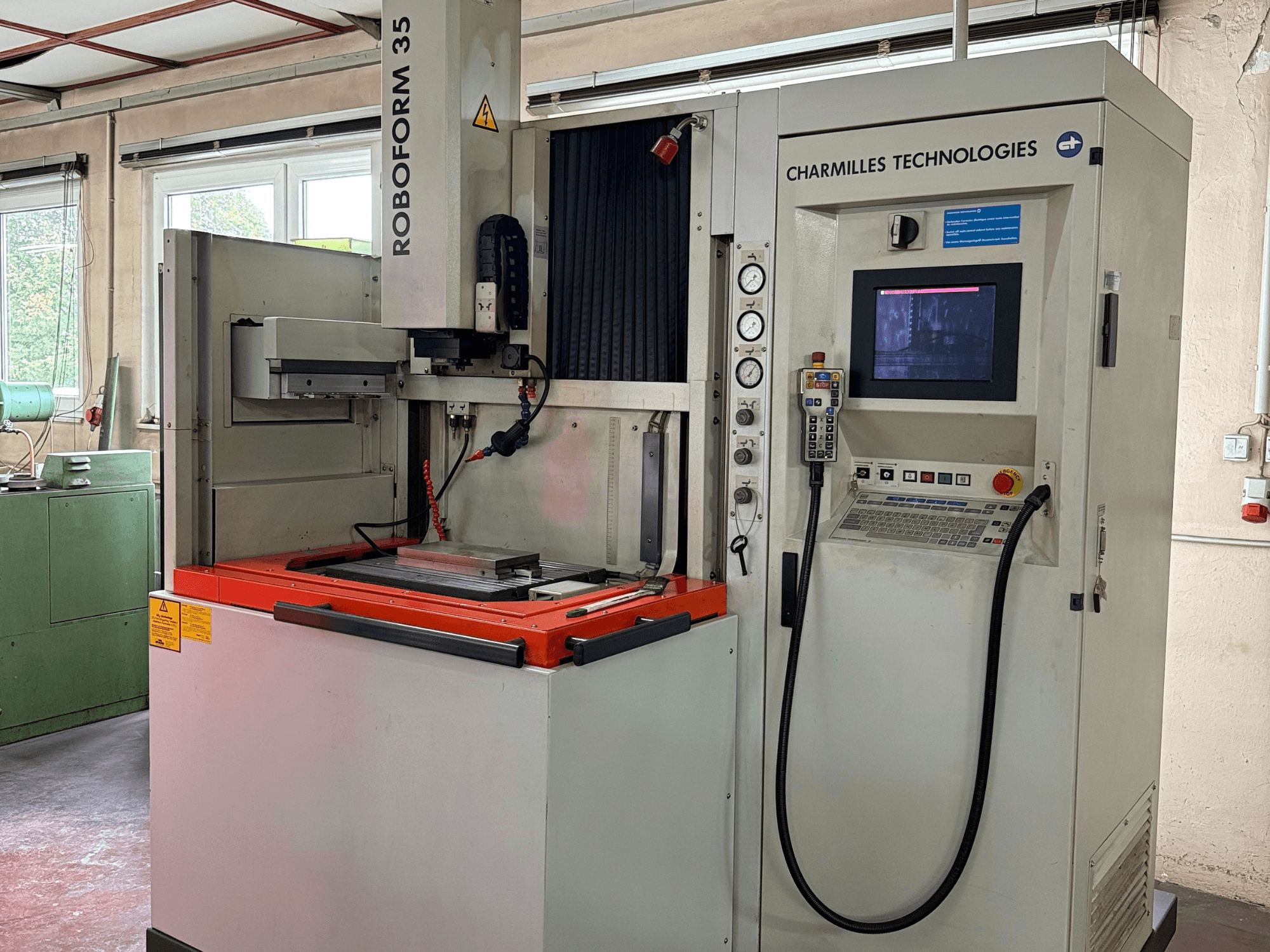 Charmilles Technologies Roboforn 35 gép, előlnézet, a vezérlőpanel, a felszerelt szerszámok és a biztonsági címkék.