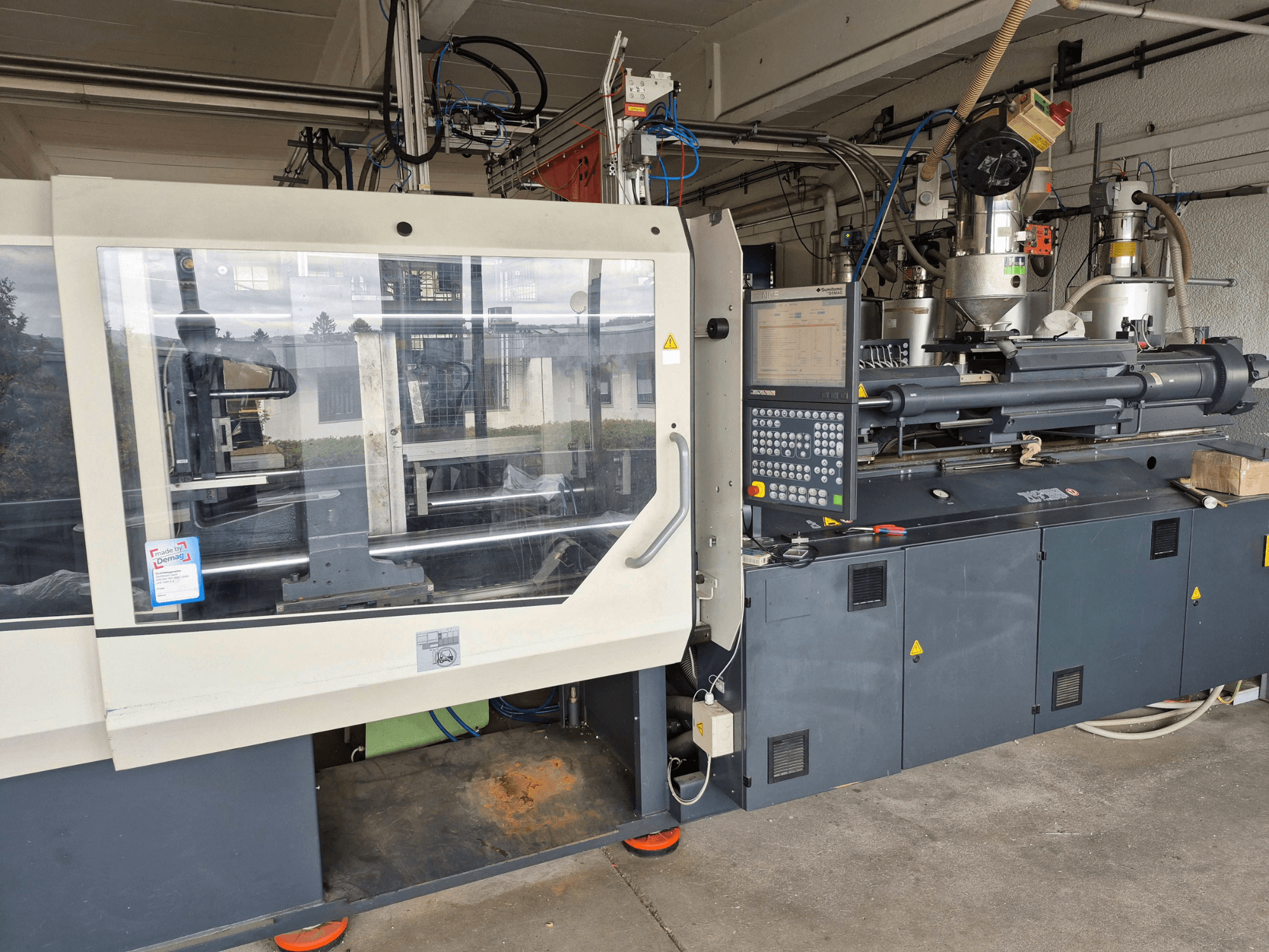 Hidraulikus fröccsöntőgép, SUMITOMO SHI DEMAG Systec 210/580-1450, elölnézet a vezérlőpanellel és a látható alkatrészekkel.