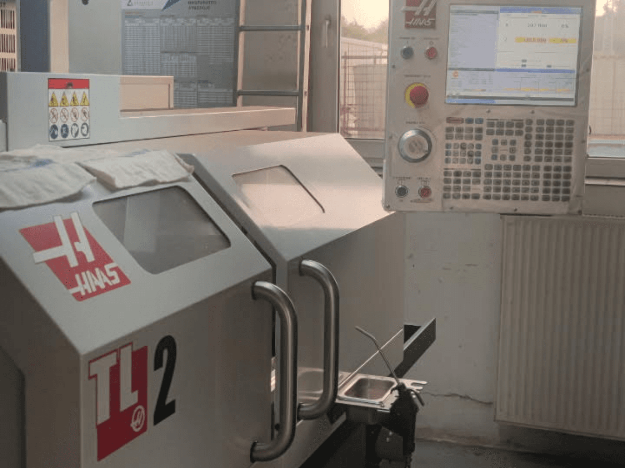Haas TL-2 vízszintes esztergagép előlnézetben, vezérlőpanel, fémház és biztonsági jelzések.