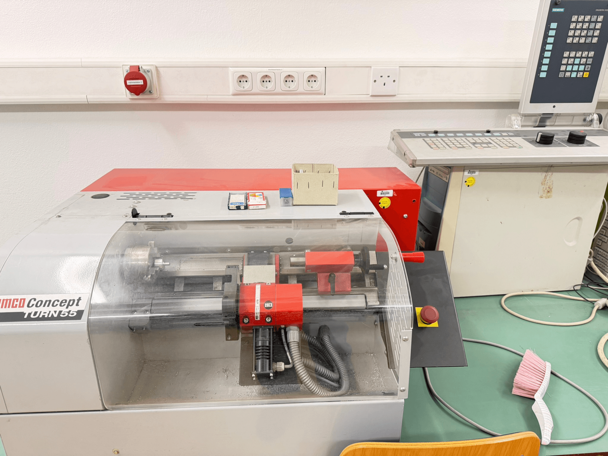 EMCO Concept Turn 55 vízszintes esztergagép piros és szürke külsővel, elölnézetben a kezelőszervek és a munkaterület.