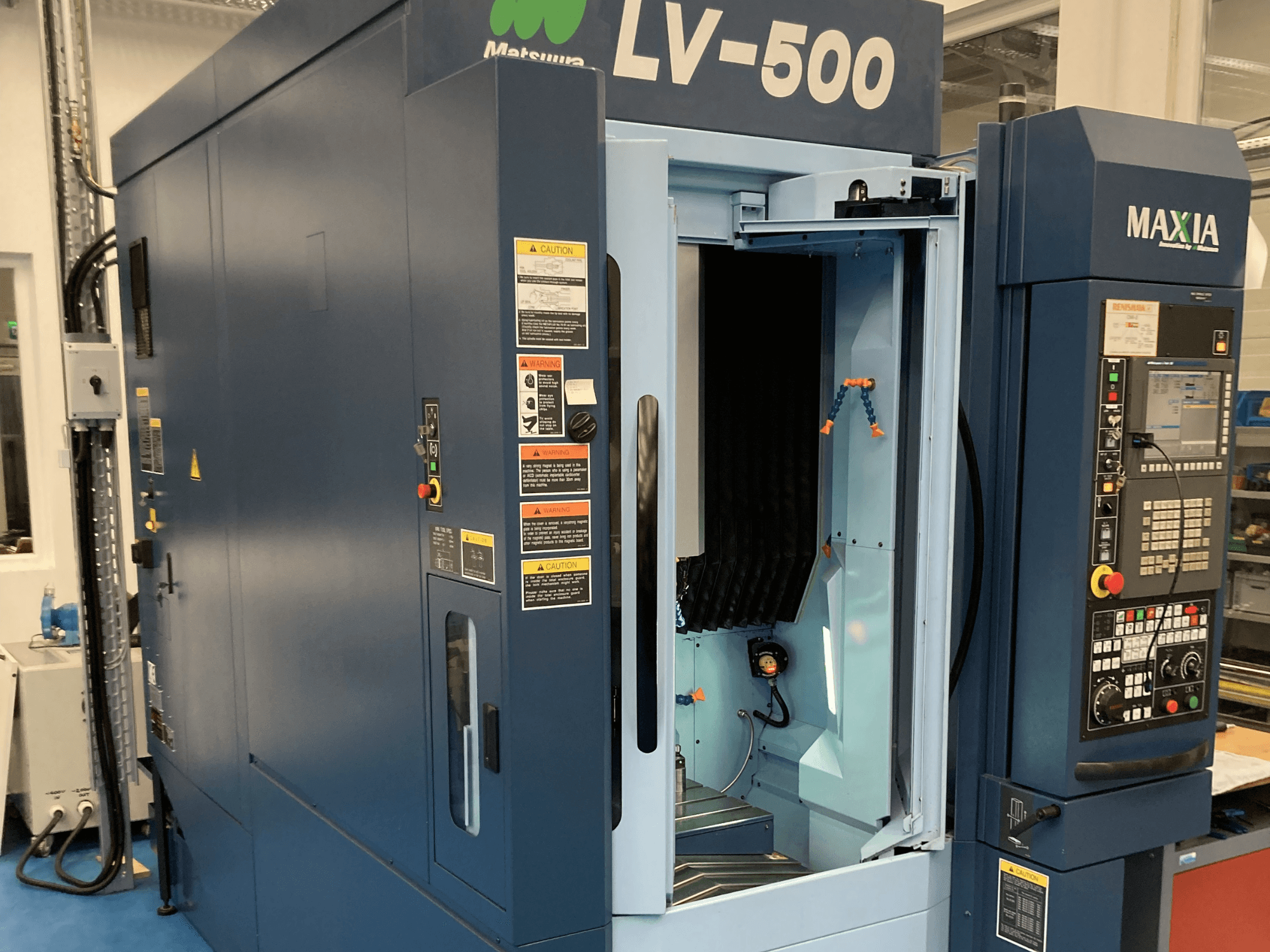Matsuura LV-500 függőleges megmunkálóközpont elölnézetből, nyitott ajtóval és gombokkal ellátott kezelőpanellel.