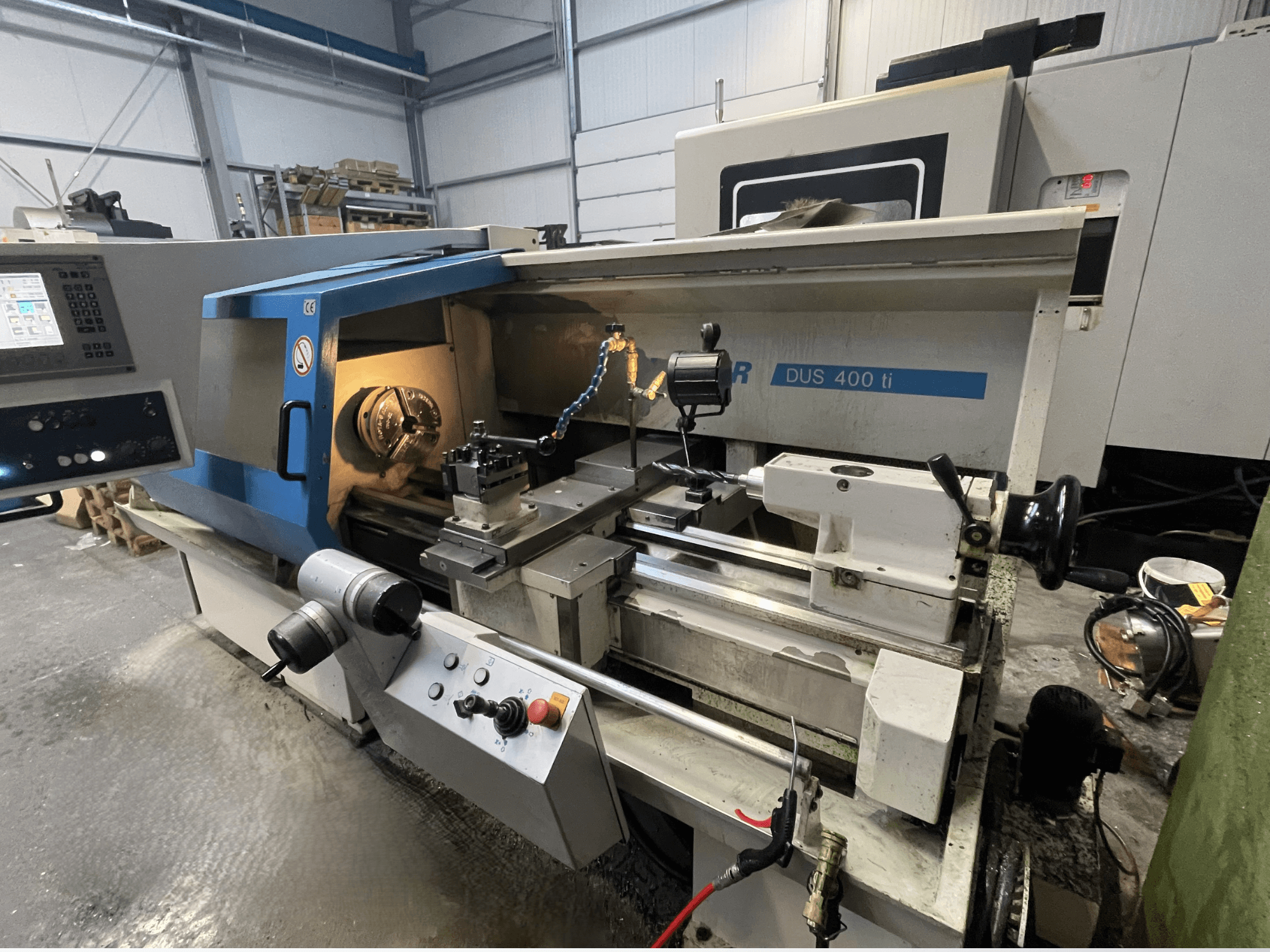 CNC esztergagép DUS 400 ti elölnézetből, vezérlőpanel, szerszámtartó és megvilágított munkaterület.