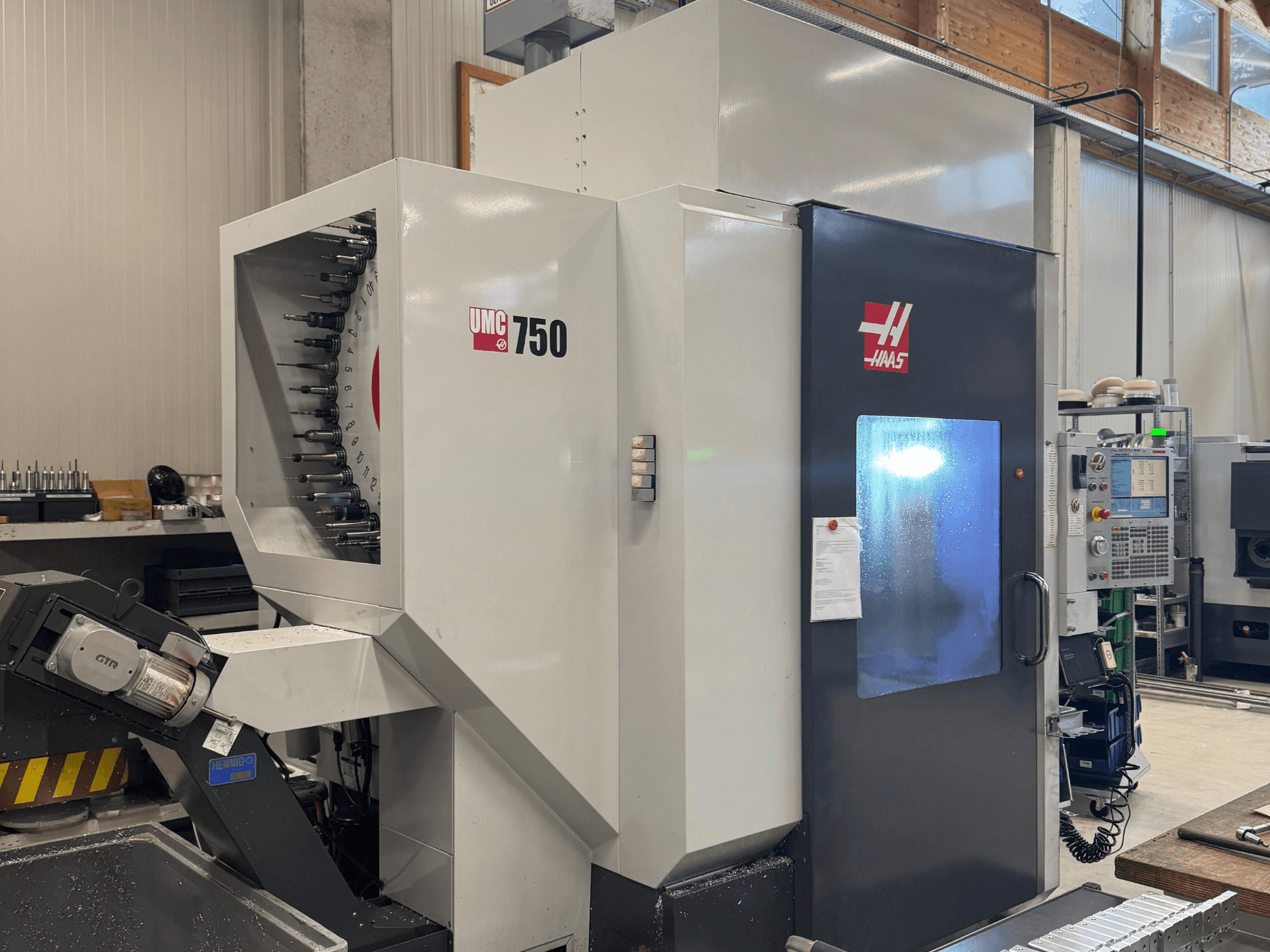 Haas UMC 750 megmunkálóközpont, előlnézet, szerszámtartó és vezérlőpanel műhelyben.