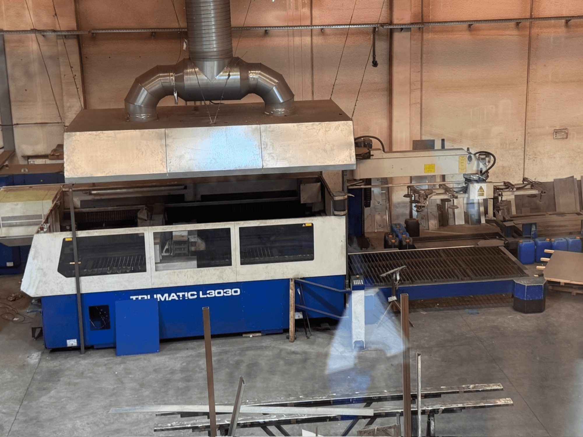TRUMPF TRUMATIC L3030 CO₂-lézervágógép egy műhelyben, elölnézetből, a vezérlőpanellel és a vágóasztallal.