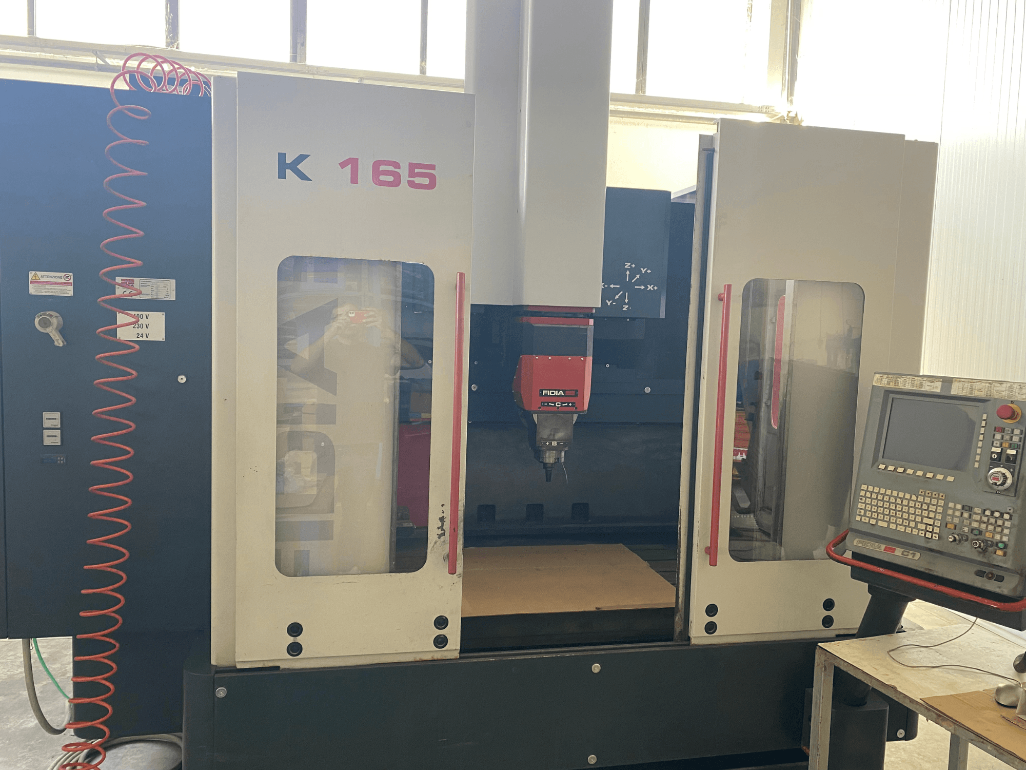 Fidia K 165 CNC-gép piros orsóval és vezérlőpanellel, szemből nézve, jól megvilágított műhelyben.