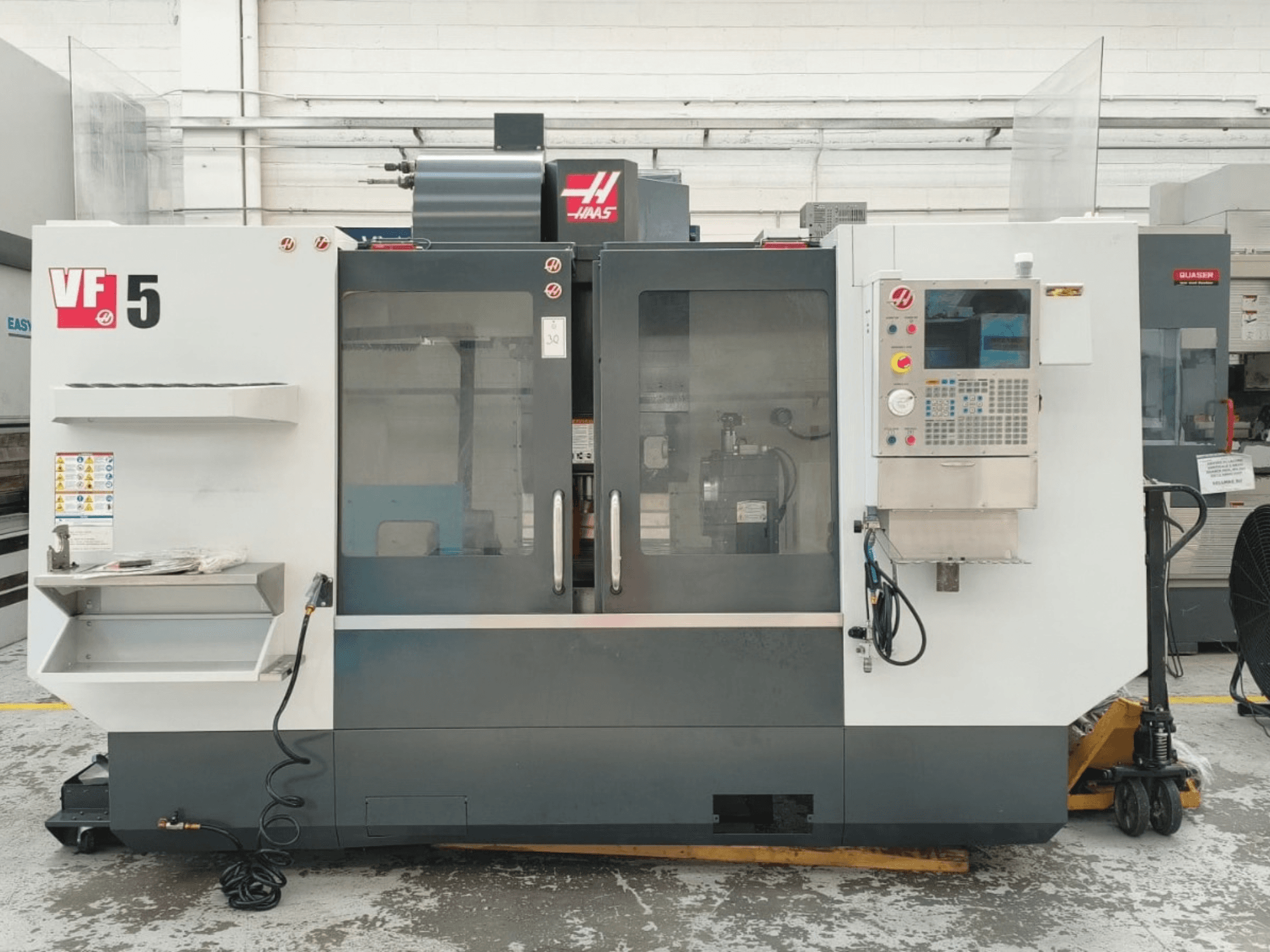 A HAAS VF 5/40 függőleges megmunkáló központ elölnézete, a vezérlőpanellel és az üvegajtókkal.
