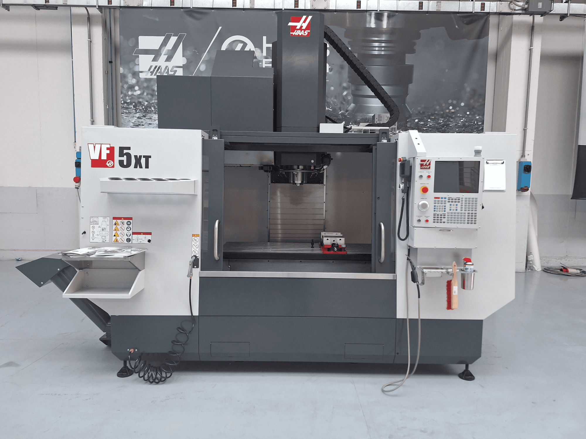 HAAS VF-5/50XT függőleges megmunkáló központ, elölnézet, amelyen látható a vezérlőpanel, az orsóterület és a szerszámtároló.
