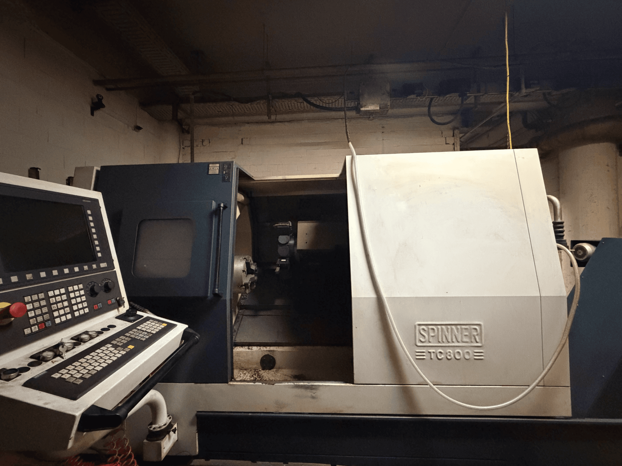 Vízszintes esztergagép SPINNER TC800, elölnézet, a vezérlőpanel látható, a gép belseje kissé feltárva.