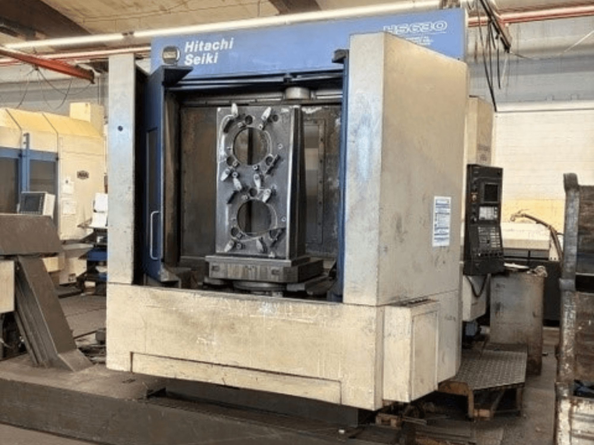 Hitachi Seiki HS630 vízszintes megmunkálóközpont, elölnézet, amelyen egy munkadarab és a vezérlőpanel látható.