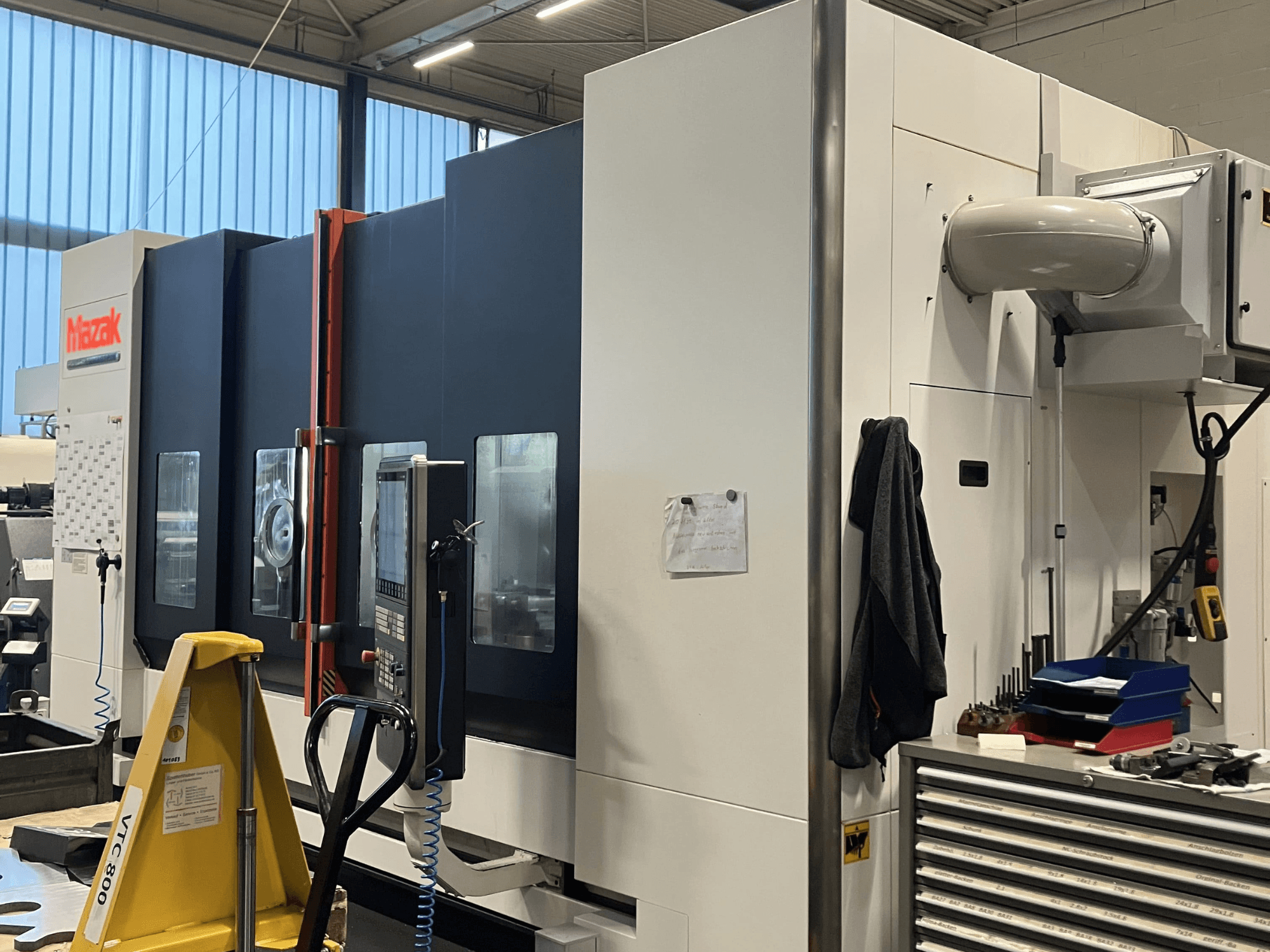 Mazak CNC-gép oldalnézetből, a vezérlőpanel és a biztonsági funkciók bemutatása műhelykörnyezetben.