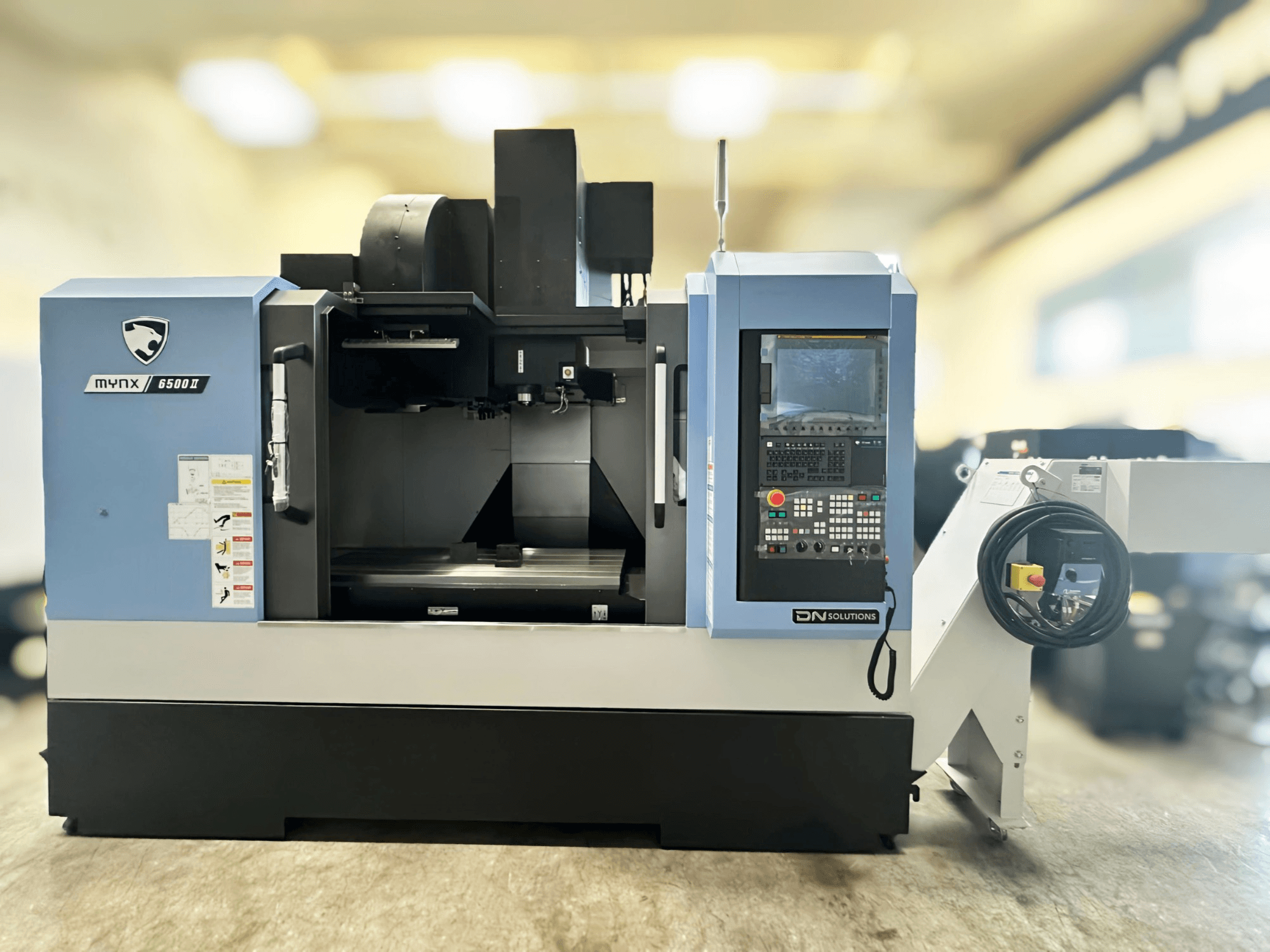 A DN SOLUTIONS MYNX 6500 II függőleges megmunkáló központ elölnézete, a vezérlőpanellel és a kezelőfelülettel.