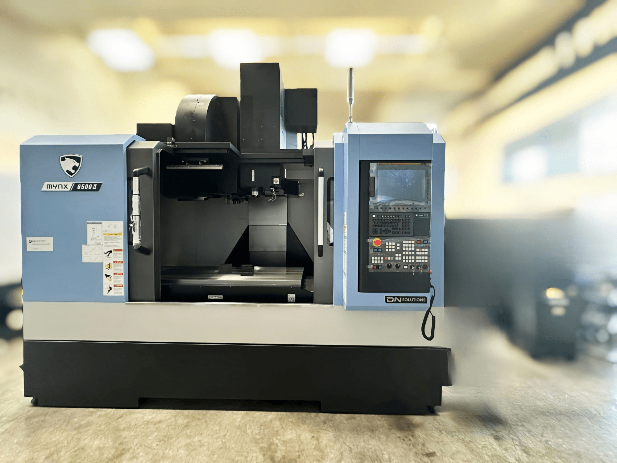 DN SOLUTIONS MYNX 6500 II függőleges megmunkáló központ, elölnézet, amelyen látható a vezérlőpanel és a munkaterület.
