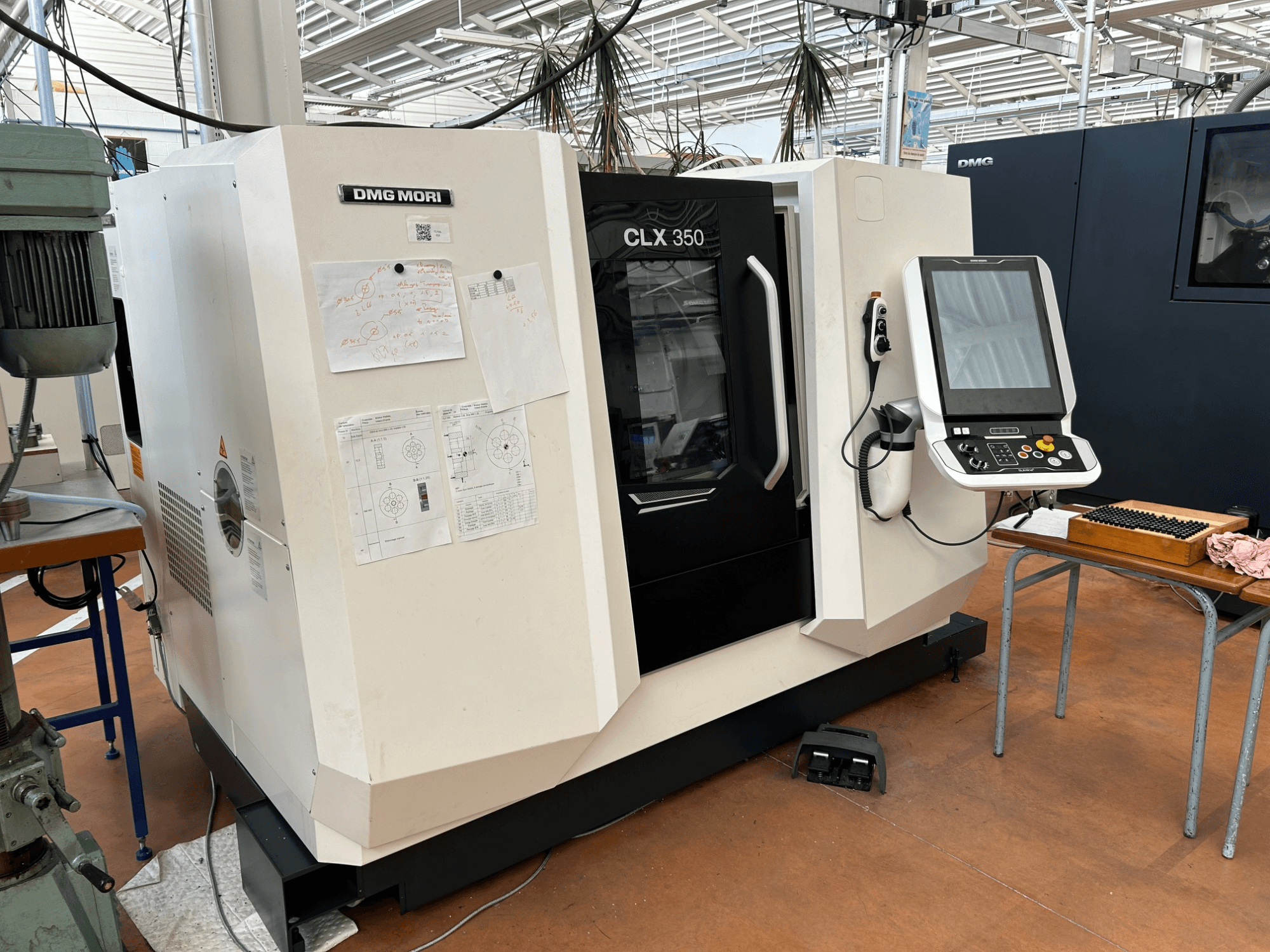 DMG MORI CLX 350 V4 vízszintes eszterga, elölnézet a vezérlőpanellel és a mellékelt műszaki dokumentumokkal.