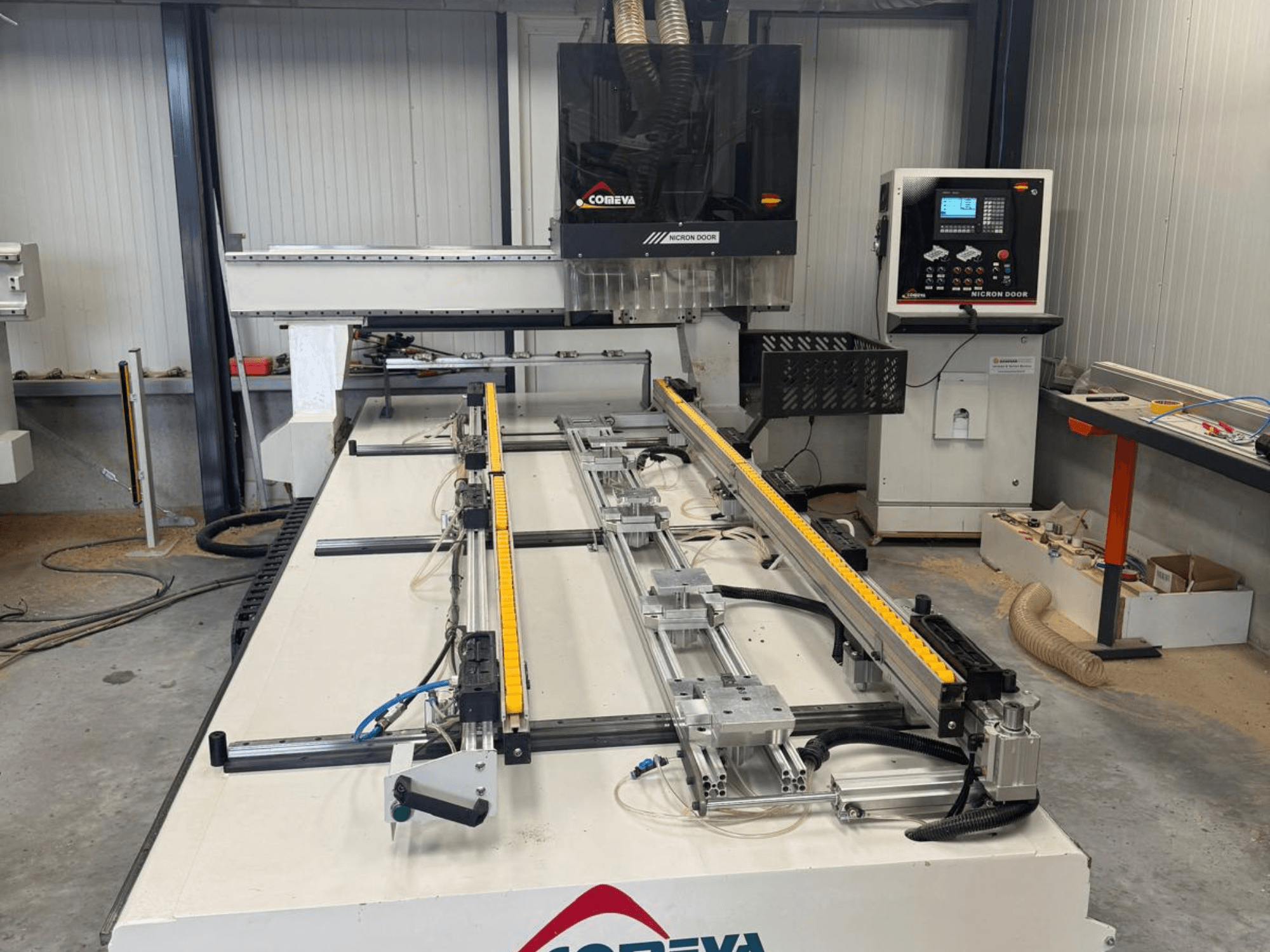 COMEVA MEX V 2100x3260 CNC faipari megmunkáló központ elölnézete, munkállomással, vezérlőpanellel és vezetősínekkel.