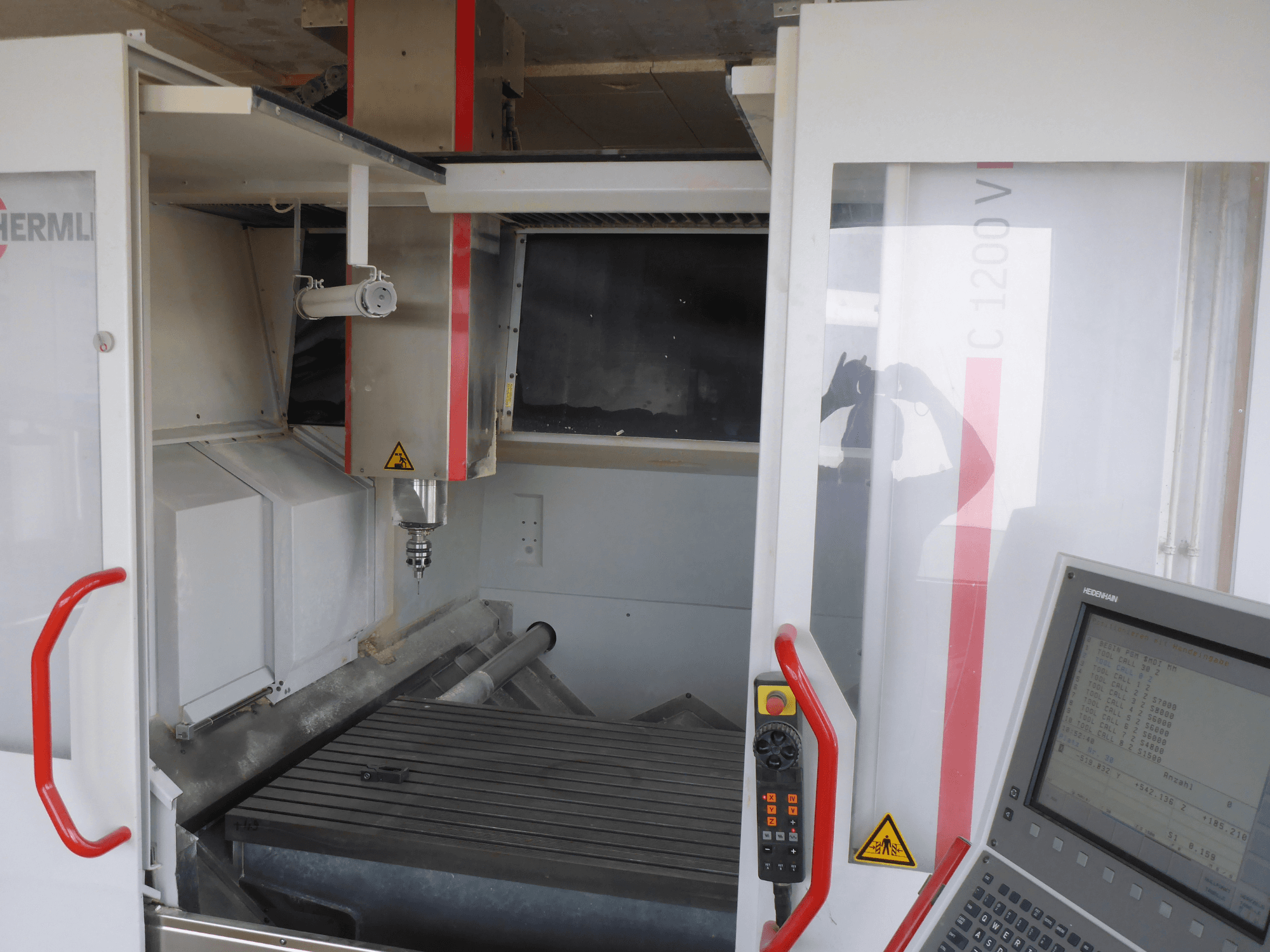 HERMLE C 1200 függőleges megmunkálóközpont belseje, szerszámtartó, vezérlőpanel és munkaasztal szemből.