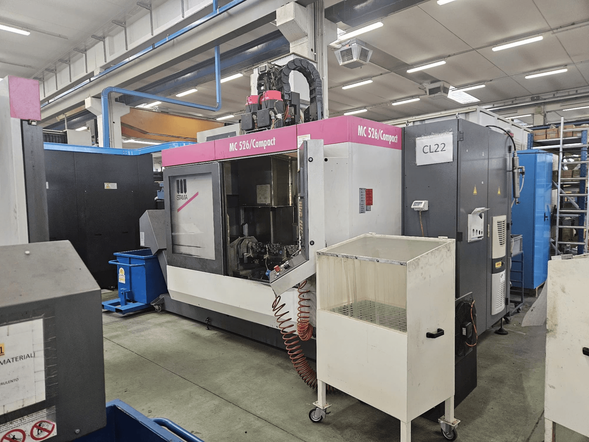MC 526 Compact CNC gép a Stama gyártótól, oldalnézet, a vezérlőpanel, a hűtőfolyadék-tartály és a szomszédos gépek.