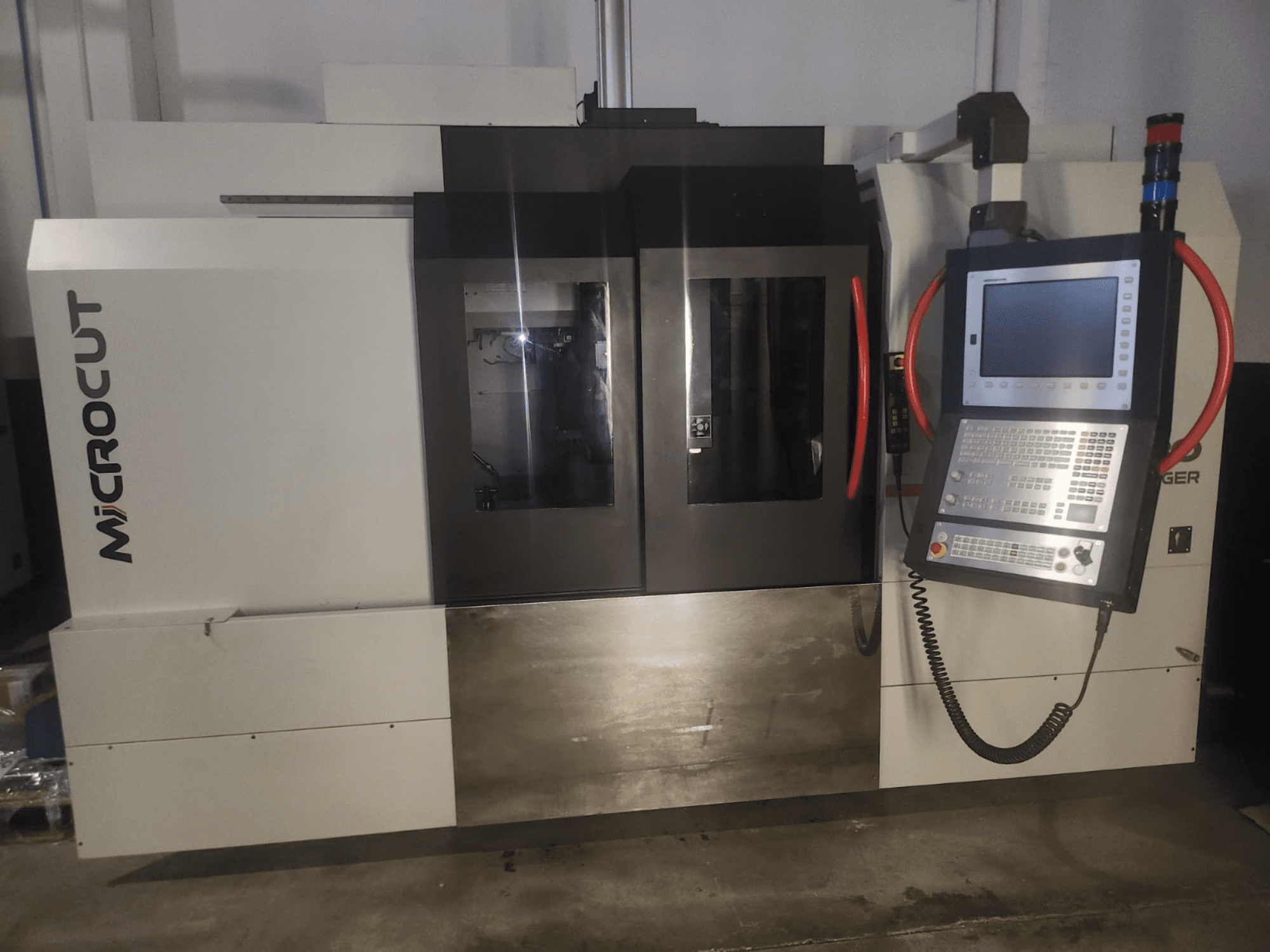 Microcut CNC-gép elölről nézve; vezérlőpanel, kettős ablakok, ipari formatervezés és fémbevonat.