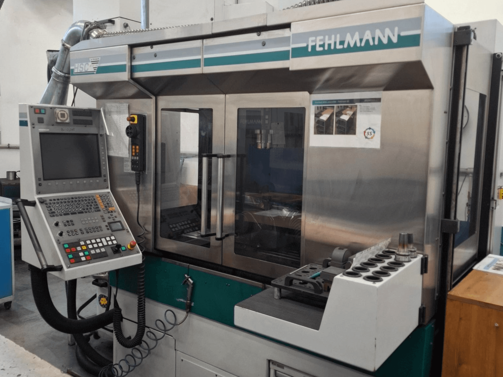 Fehlmann HSC 20 CNC-gép, elölnézet, vezérlőpanel, fémház és több nyílással ellátott szerszámtartó.