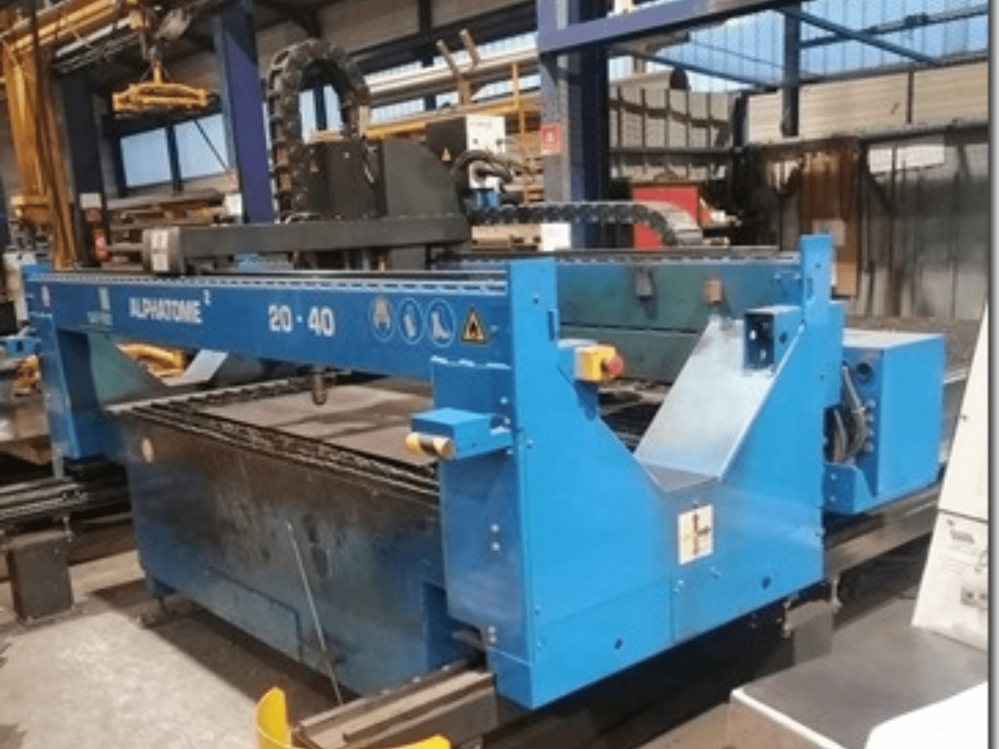 Kék ALPHATOME 20-40 CNC gép, elölnézetben, a vágási terület és a vezérlőpanel látható, precíziós gyártáshoz tervezve.