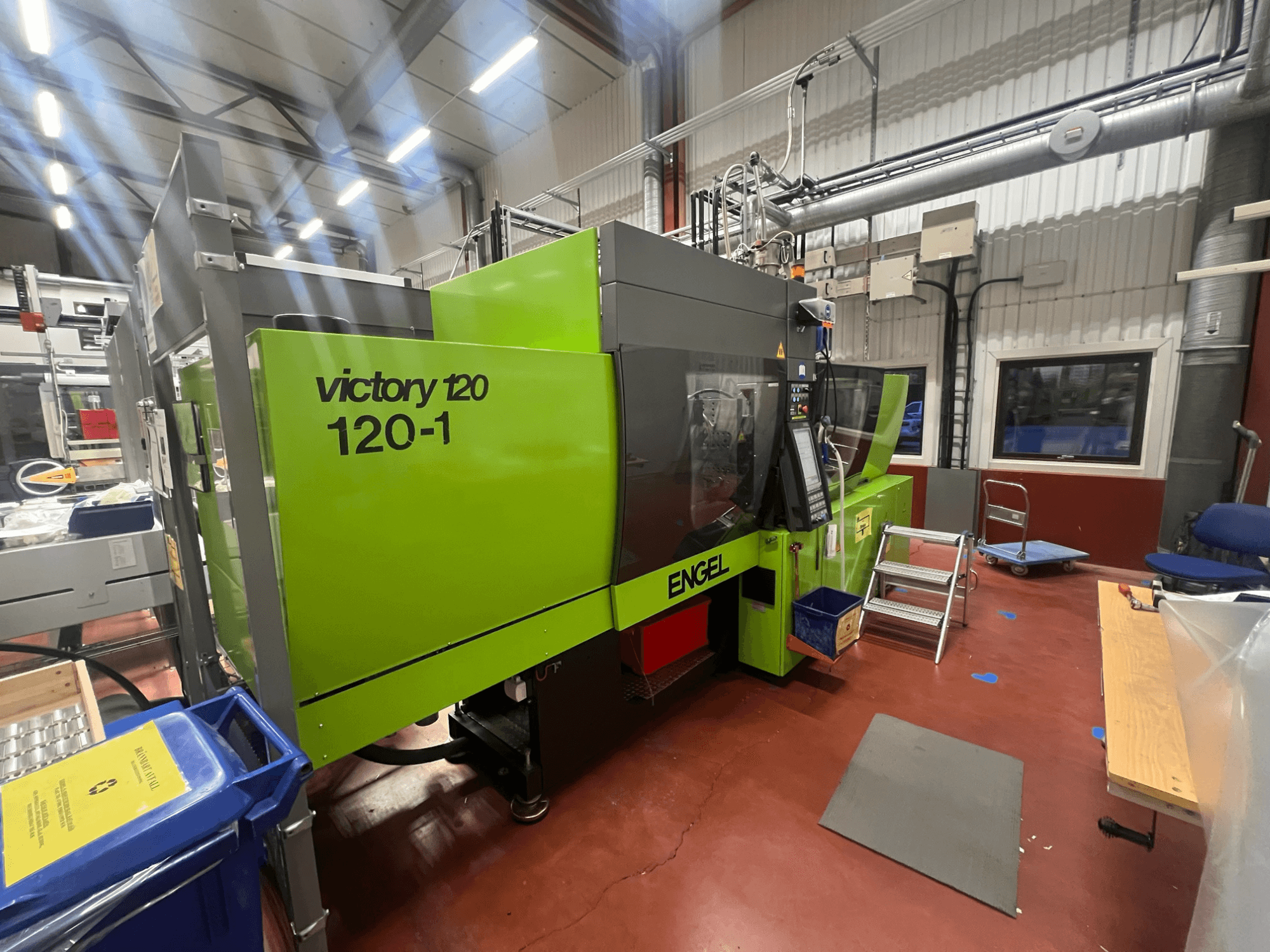 Zöld ENGEL Victory 120-1 fröccsöntőgép, elölnézetben, vezérlőpanellel és lépcsőkkel, ipari környezetben.