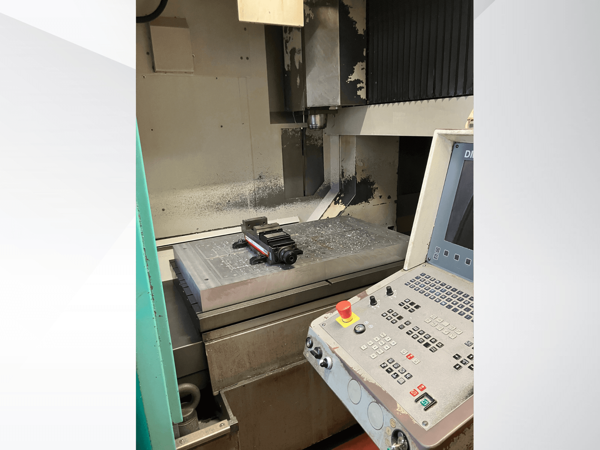 DMG DMC 100 V hi-dyn függőleges megmunkáló központ, oldalnézet, amelyen látható a vezérlőpanel és a munkapadon elhelyezett fém munkadarab.