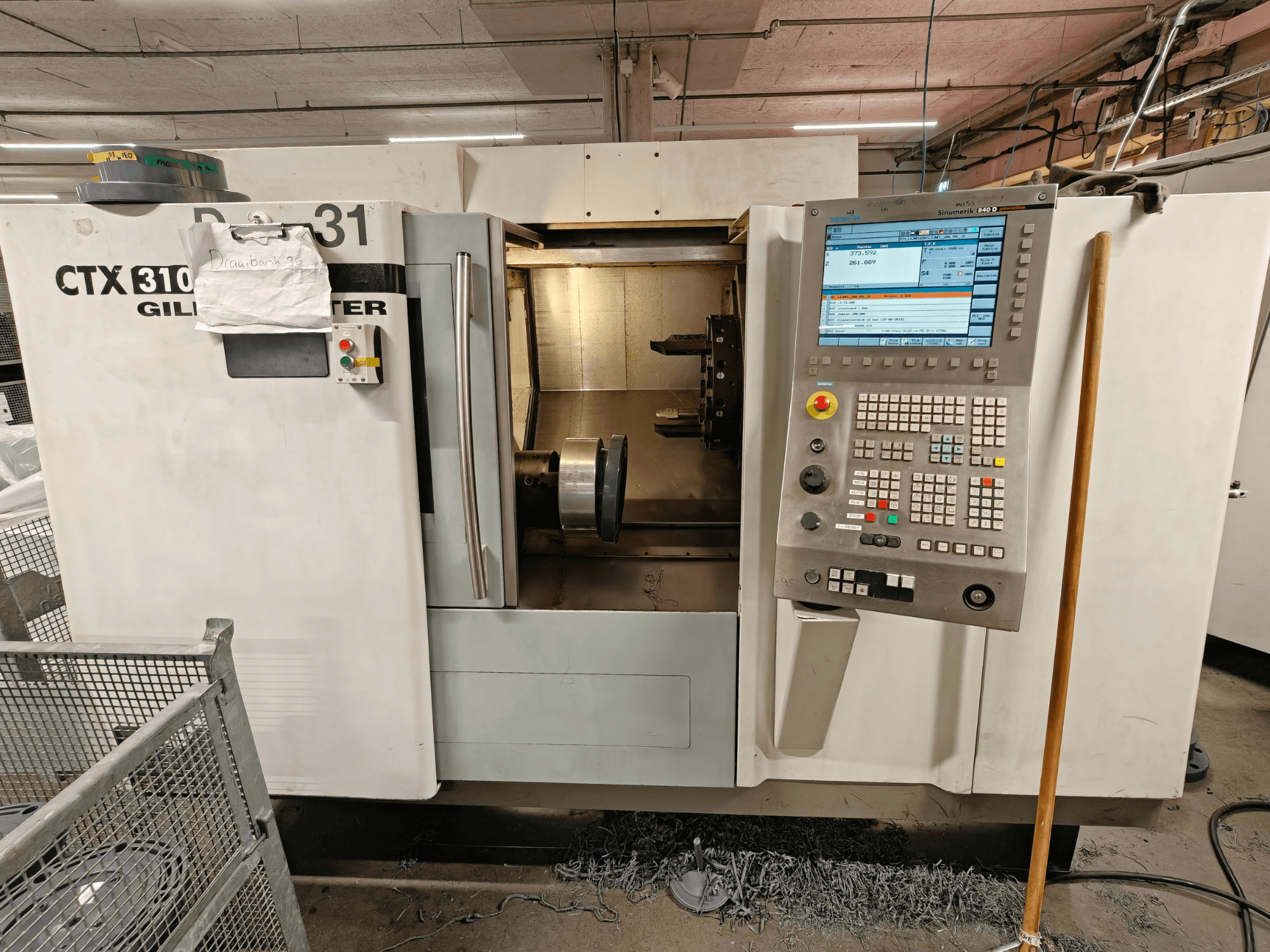 Gildemeister CTX 310 vízszintes esztergagép, elölnézet a vezérlőpanellel, a szerszámok és a belső munkaterület látható.