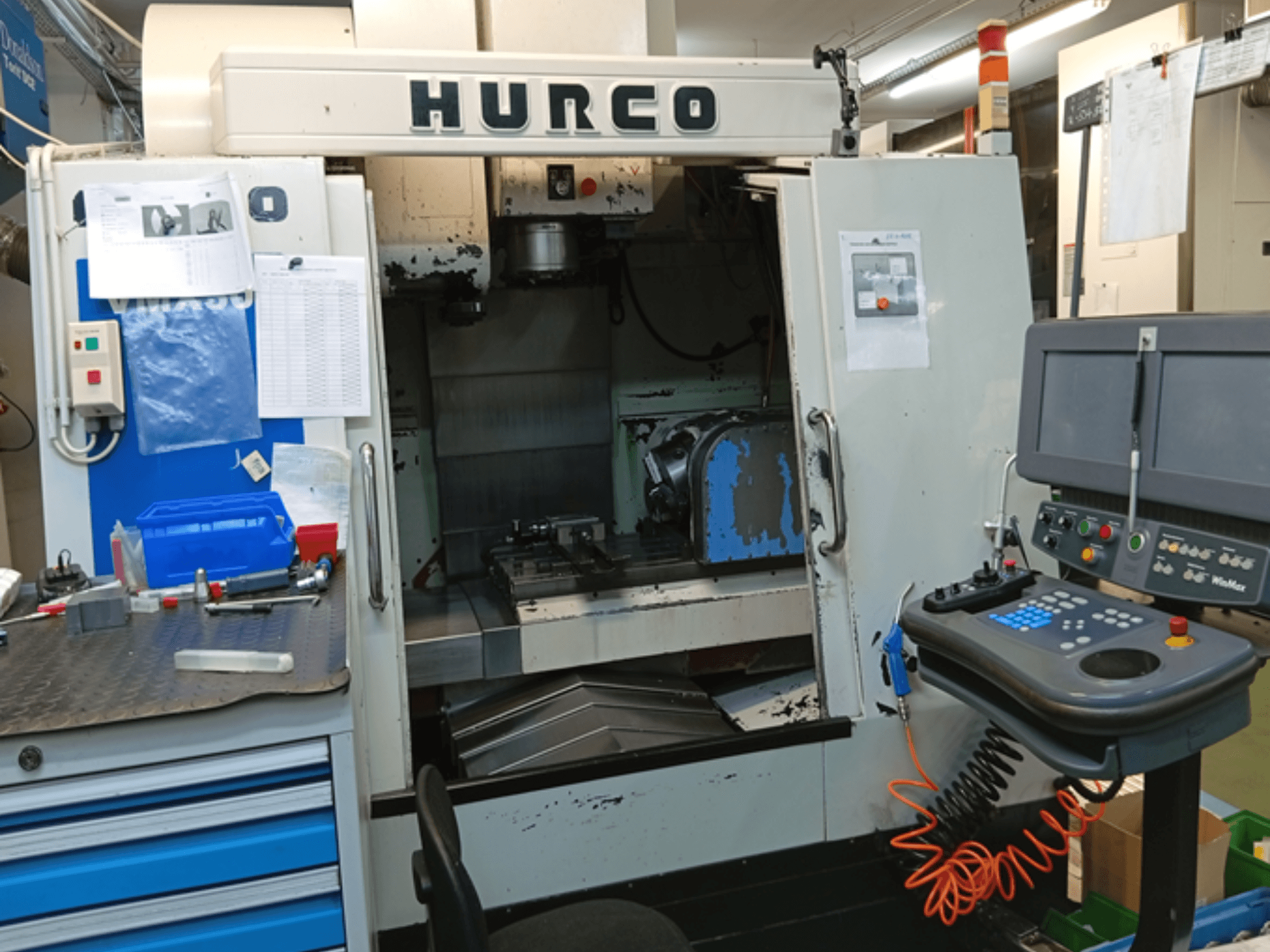 Hurco VMX 30T függőleges megmunkálóközpont, előlnézet, a vezérlőpanel, a munkaterület és a részben nyitott ajtó.