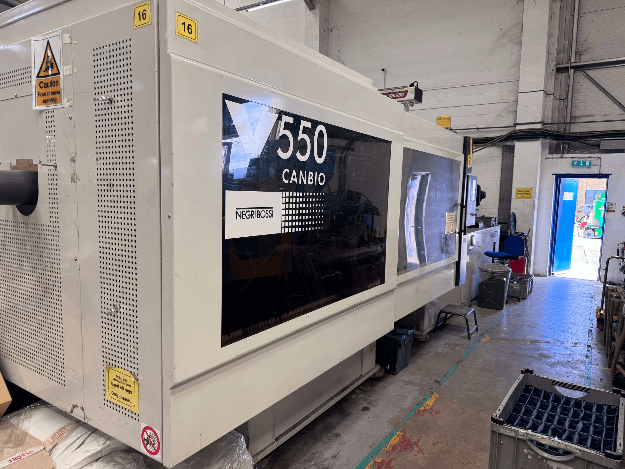 Negri Bossi 5500H-4250 hidraulikus fröccsöntőgép, elölnézet, amelyen látható a vezérlőpanel és a figyelmeztető táblák.