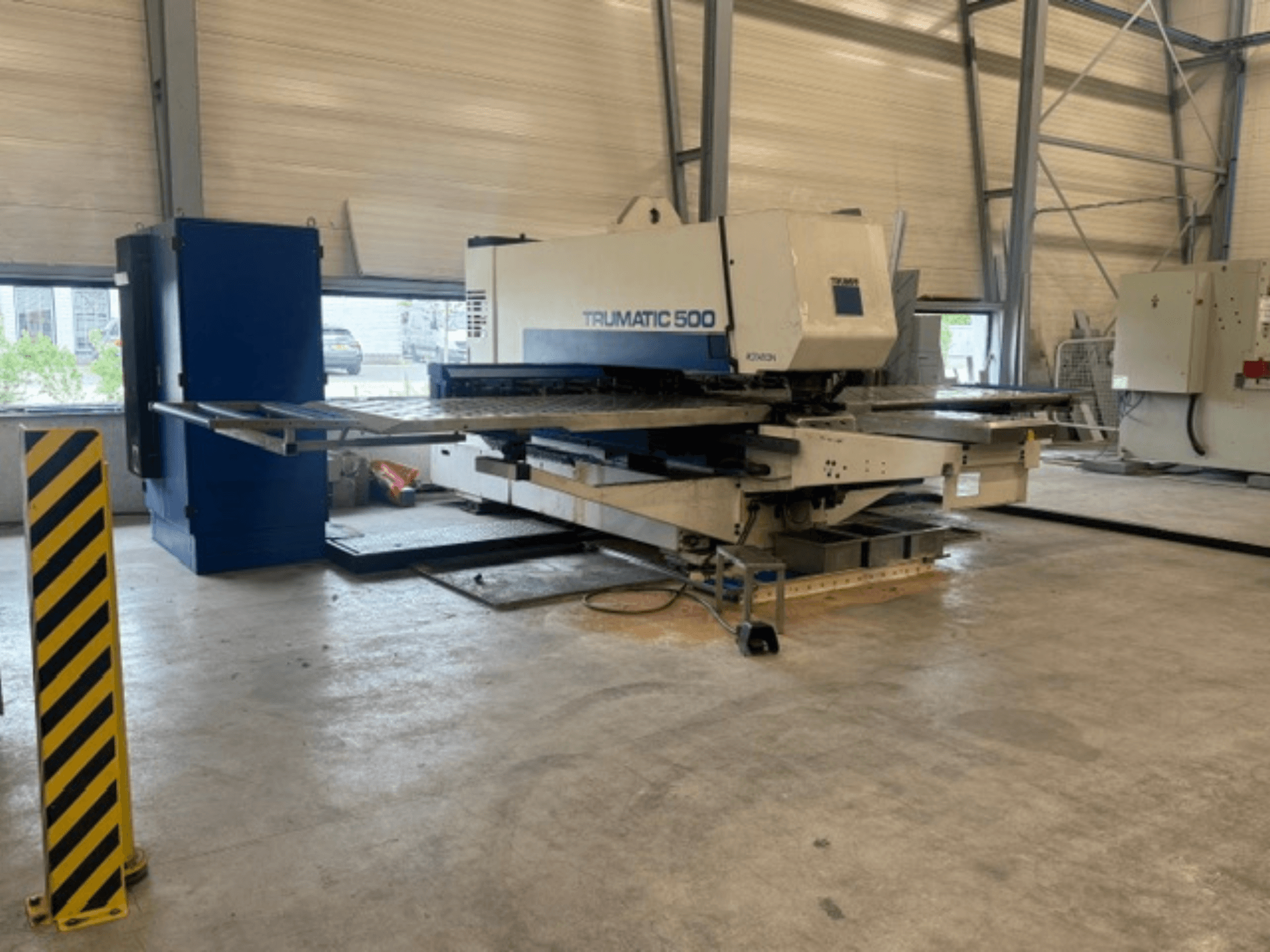 TRUMPF Trumatic 500 CNC lyukasztógép egy műhelyben, oldalnézetből, amelyen látható a gép és a sárga csíkos biztonsági oszlop.