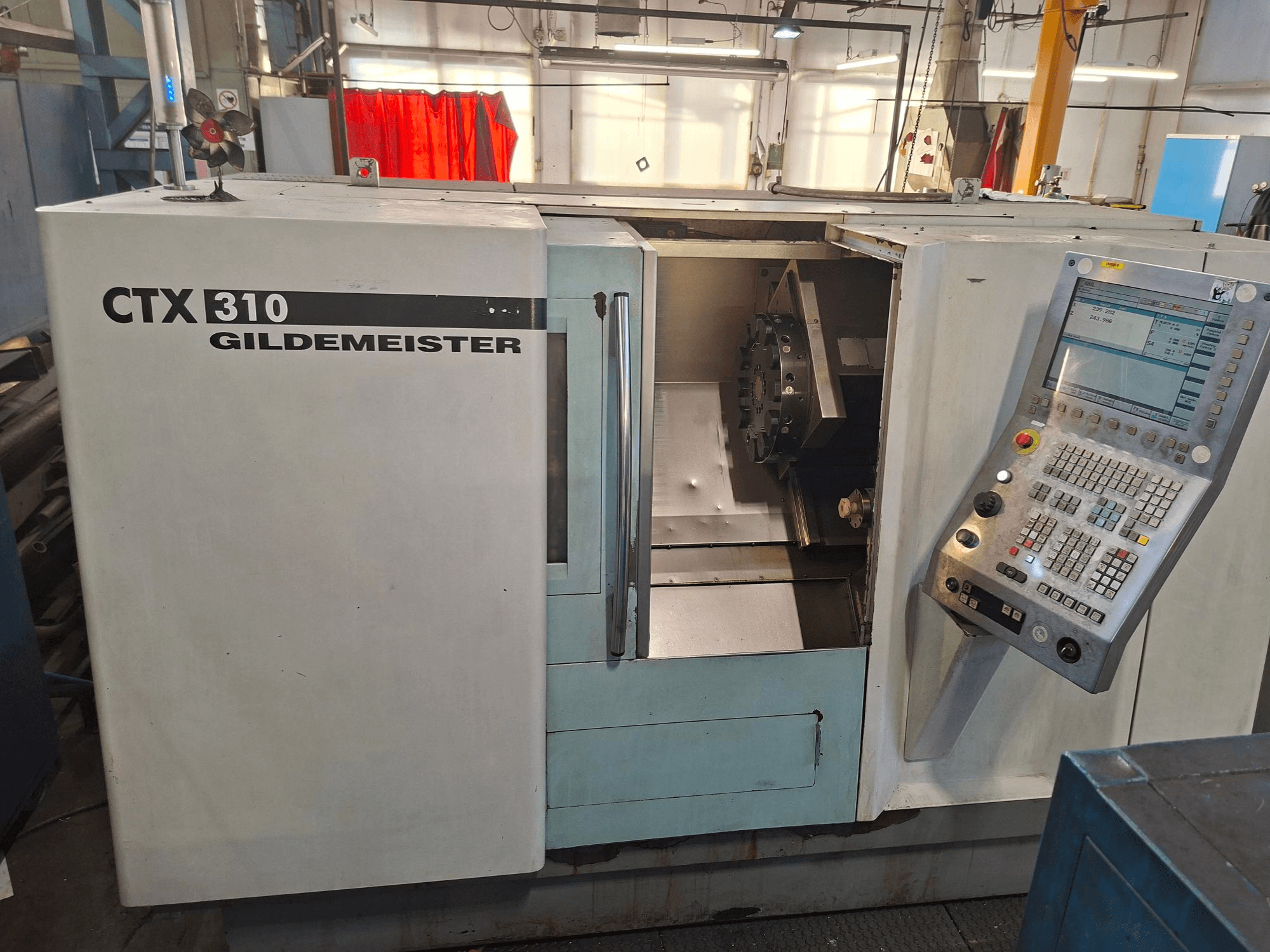 Vízszintes esztergagép DMG CTX 310, elölnézet, kezelőpanel és nyitott hozzáférés a munkaterülethez.