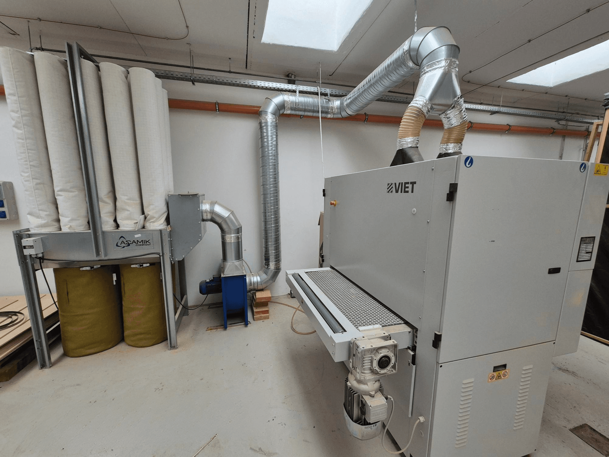 Viet porelszívó rendszer hengeres szűrőkkel és ezüst színű kipufogóval, szemből nézve műhelyben.