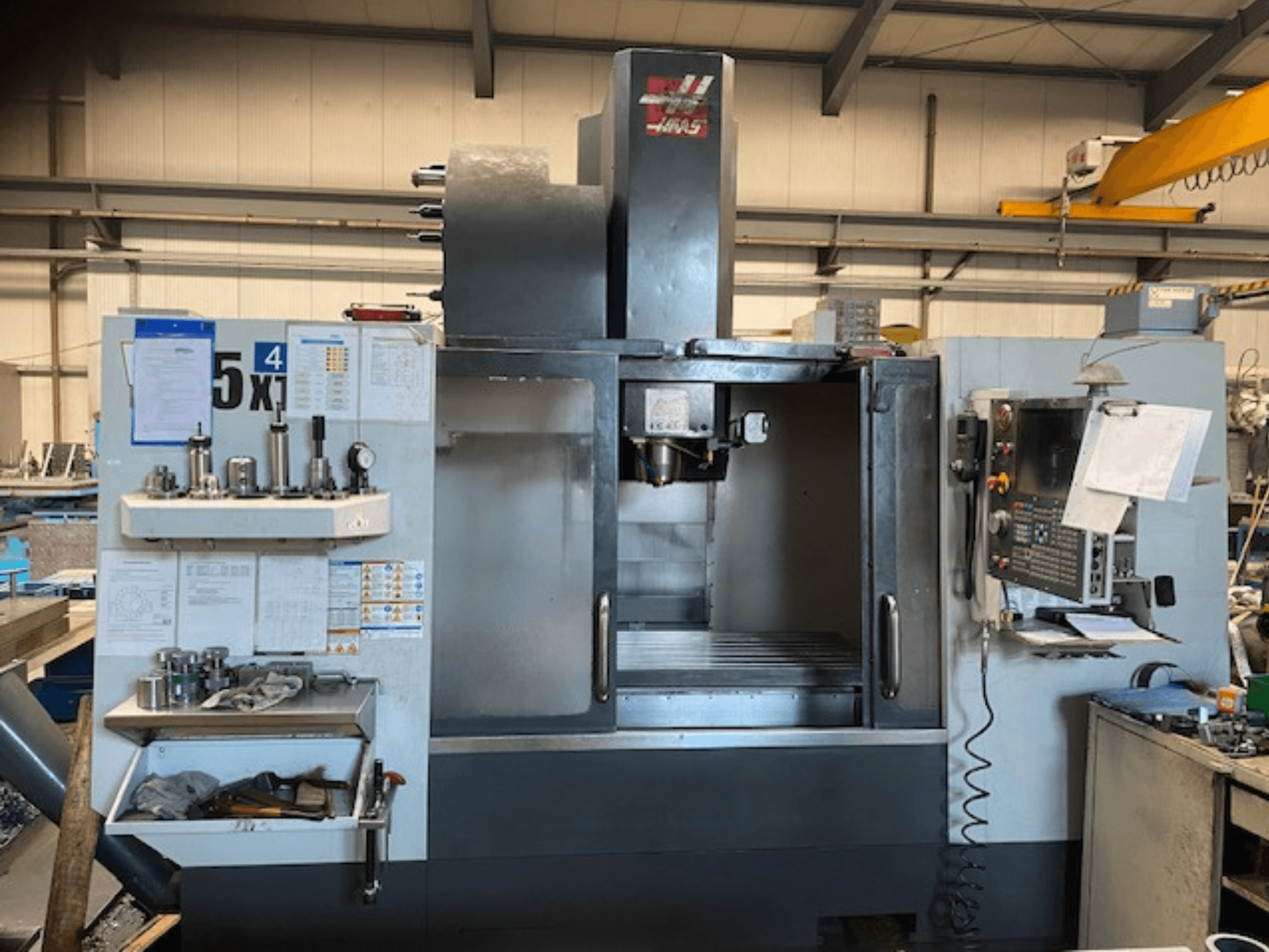 Haas VF-5 függőleges megmunkálóközpont, előlnézet, a vezérlőpanel, a szerszámtároló és az orsó területének bemutatása.