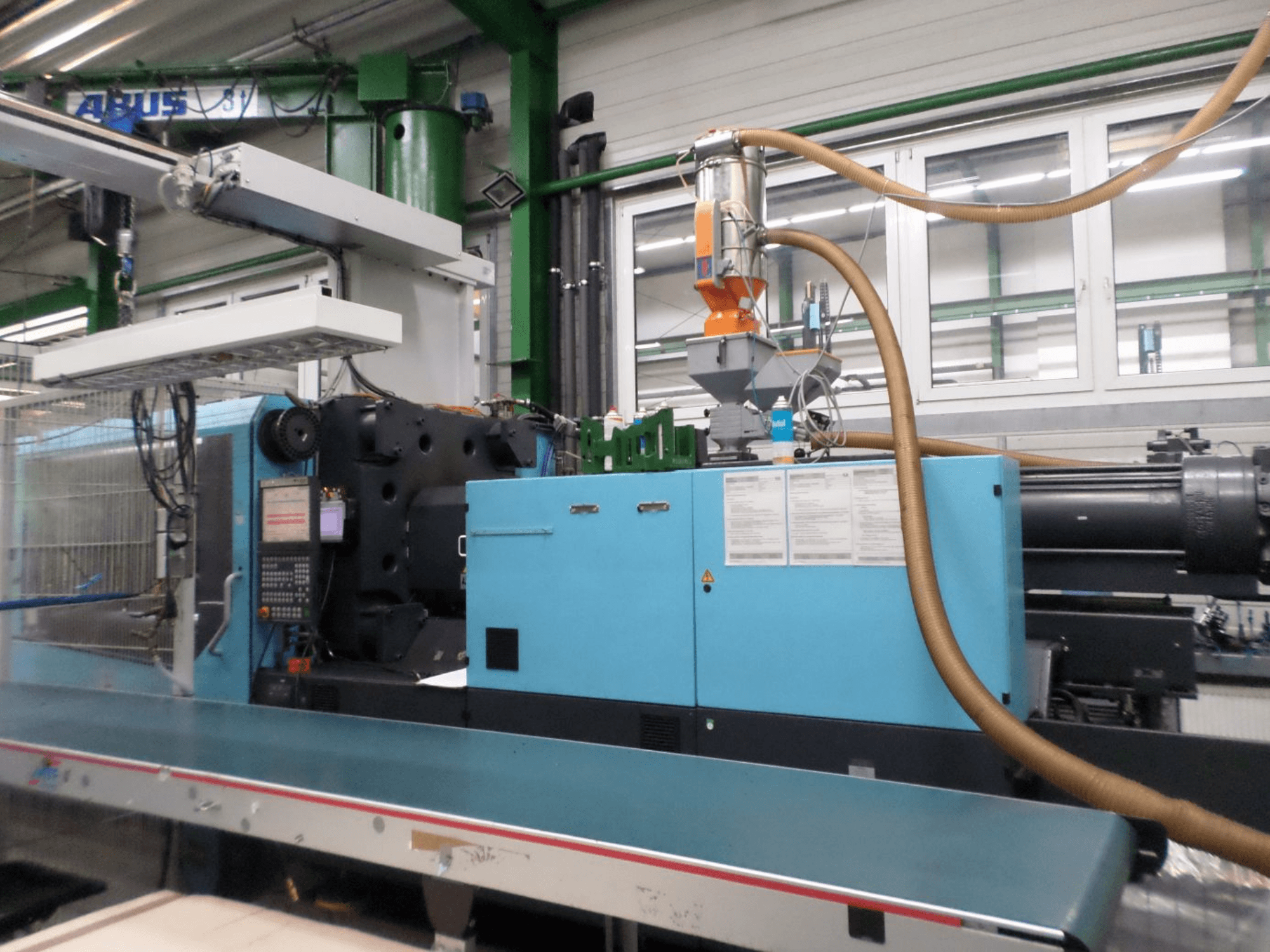 A DEMAG D 420 hidraulikus fröccsöntőgép elölnézete, amelyen látható a vezérlőpanel, a betöltőtartály és a hidraulikus alkatrészek.