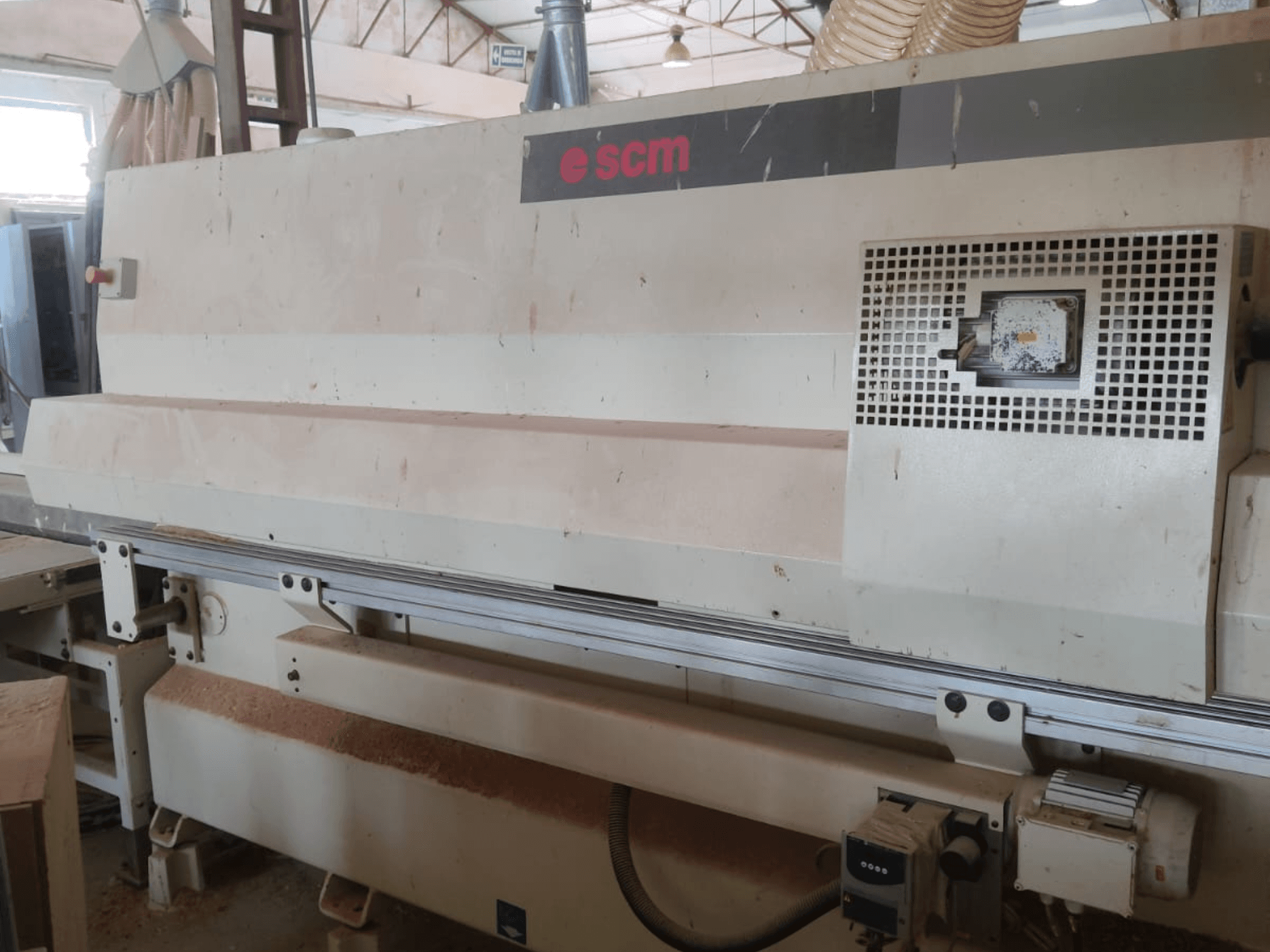 SCM Windor60 CNC faipari megmunkáló központ, elölnézet. A képen láthatók a gép vezérlőelemei és a porelszívó rendszer, alatta pedig a faforgácsok.
