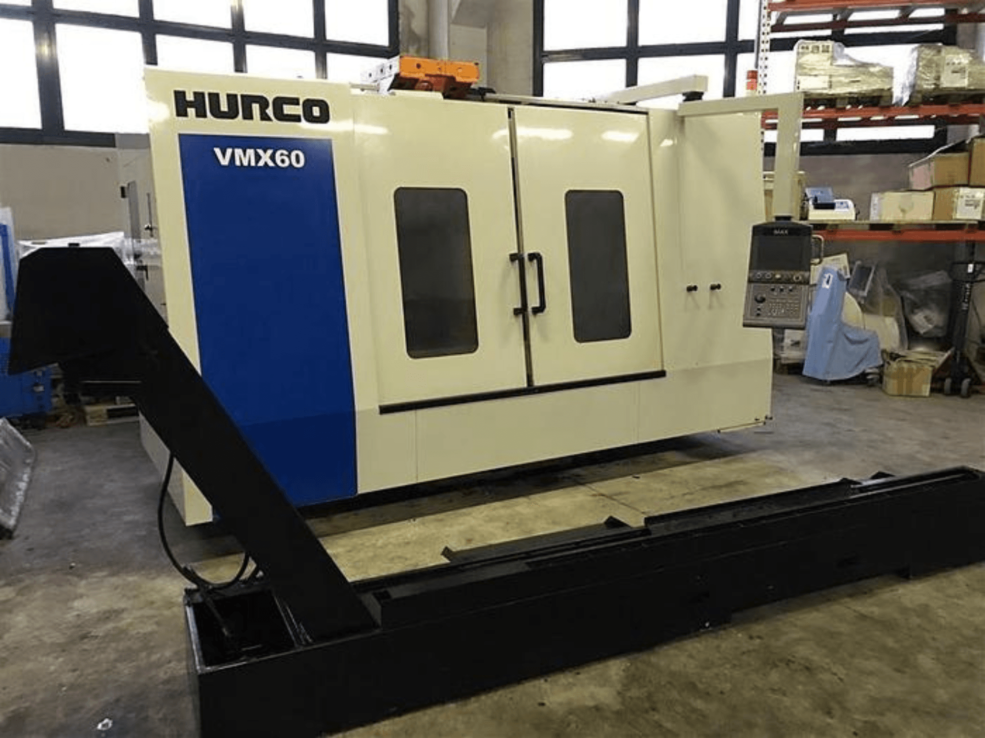 HURCO VMX60 CNC-gép egy műhelyben, elölnézetben, vezérlőpanellel és a hozzáerősített fekete tartó sínnel.