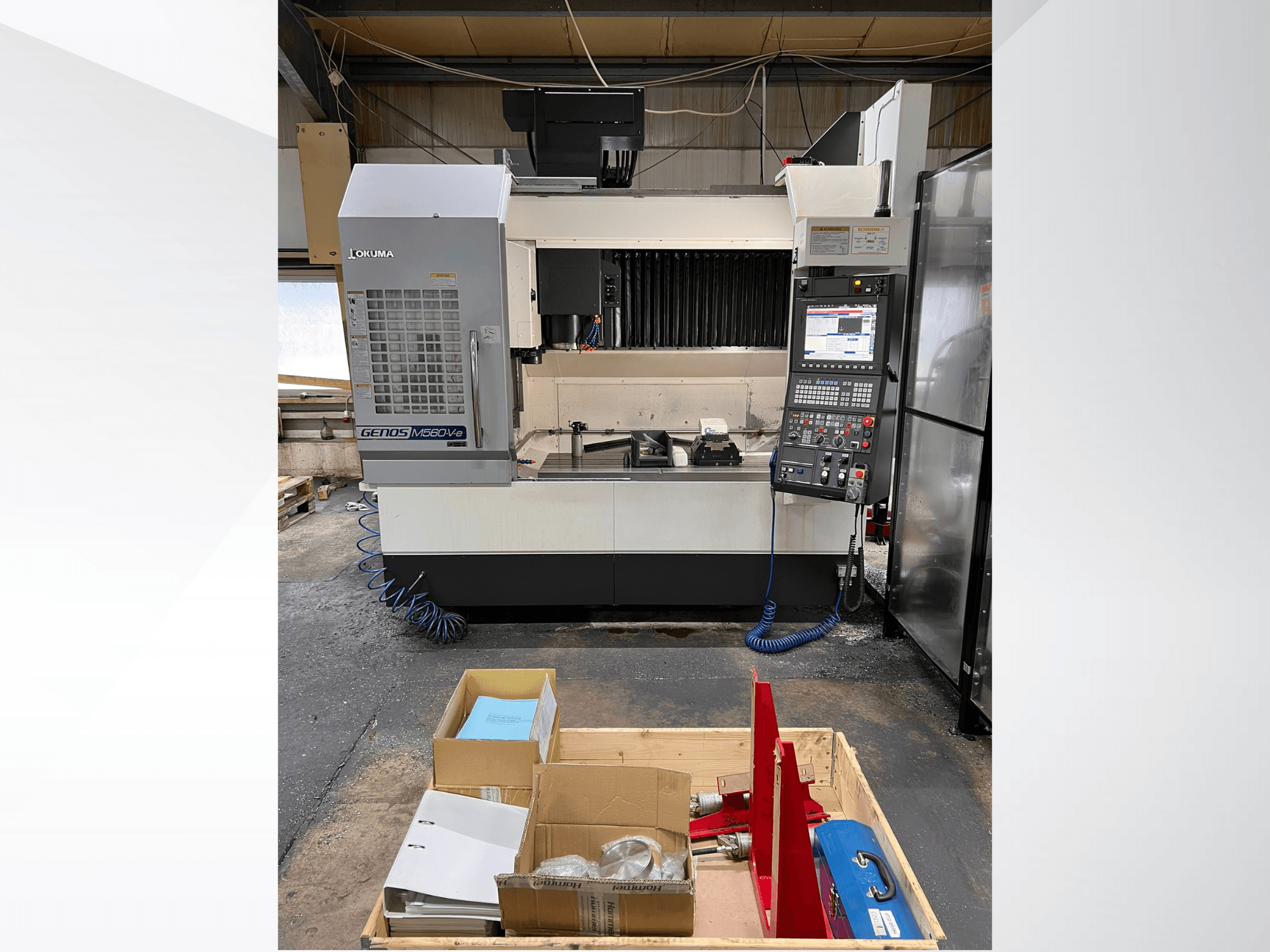 Okuma GENOS M460V-5 függőleges megmunkálóközpont, elölnézet, a vezérlőpanel látható, a szerszámok a munkaasztalon.