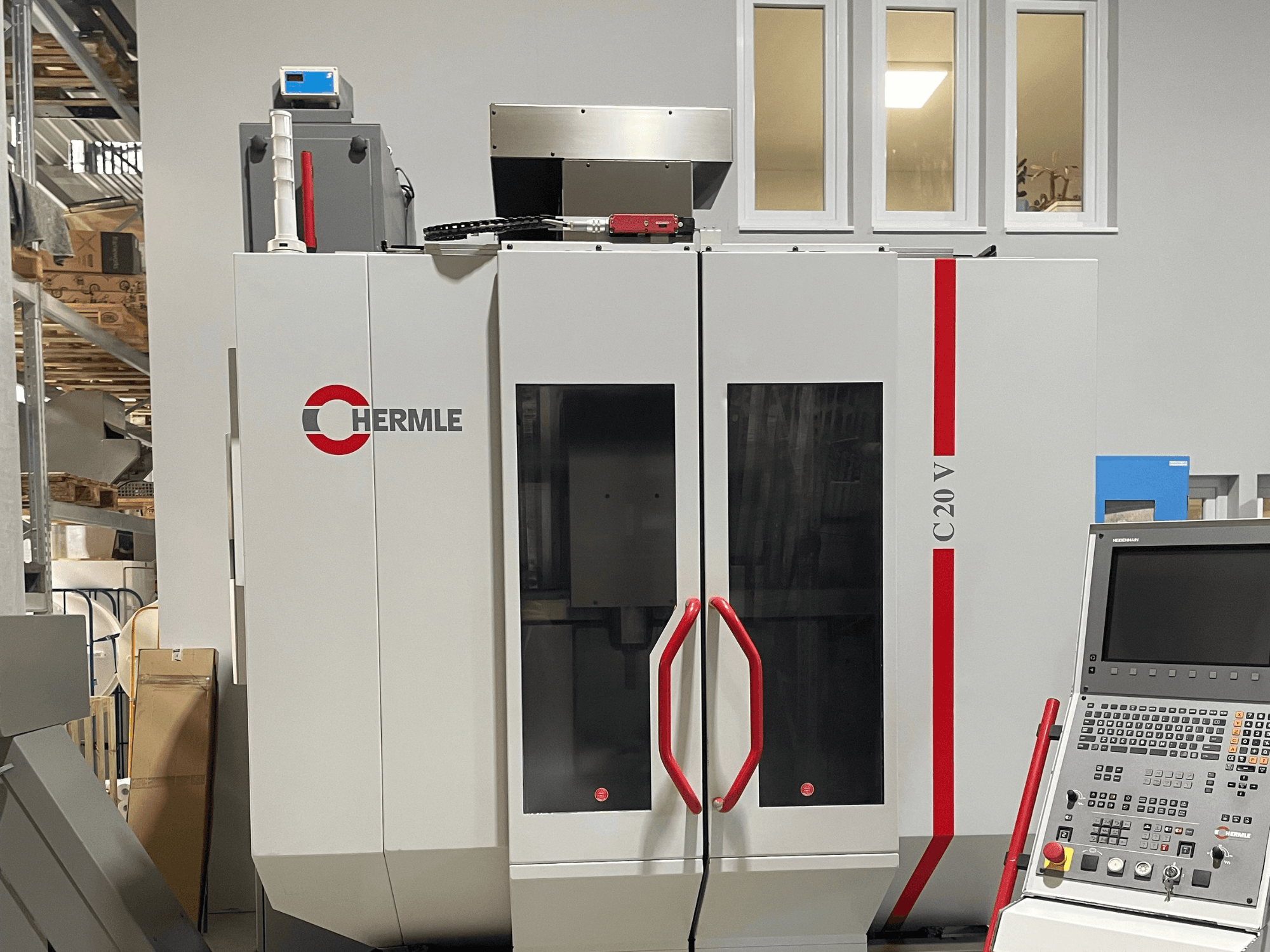 Chermle C20 V CNC-gép, előlnézet, vezérlőpanel és piros fogantyúk; ipari kivitel, nagy üvegajtókkal.