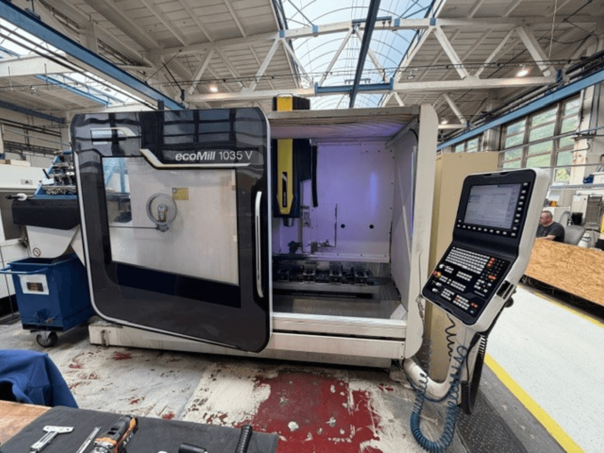 A DMG MORI ecoMill 1035V függőleges megmunkáló központ elölnézete nyitott ajtóval, amelyen látható a vezérlőpult és a belső munkaterület.
