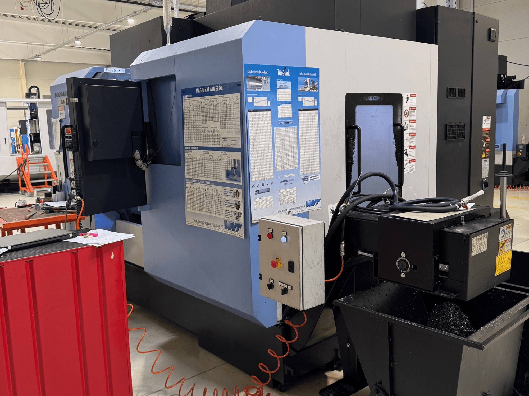 DOOSAN DNM350/5AX maró-esztergáló központ, oldalnézet, amelyen látható a vezérlőpanel és a hűtőfolyadék-tartály, valamint a működés részletei.