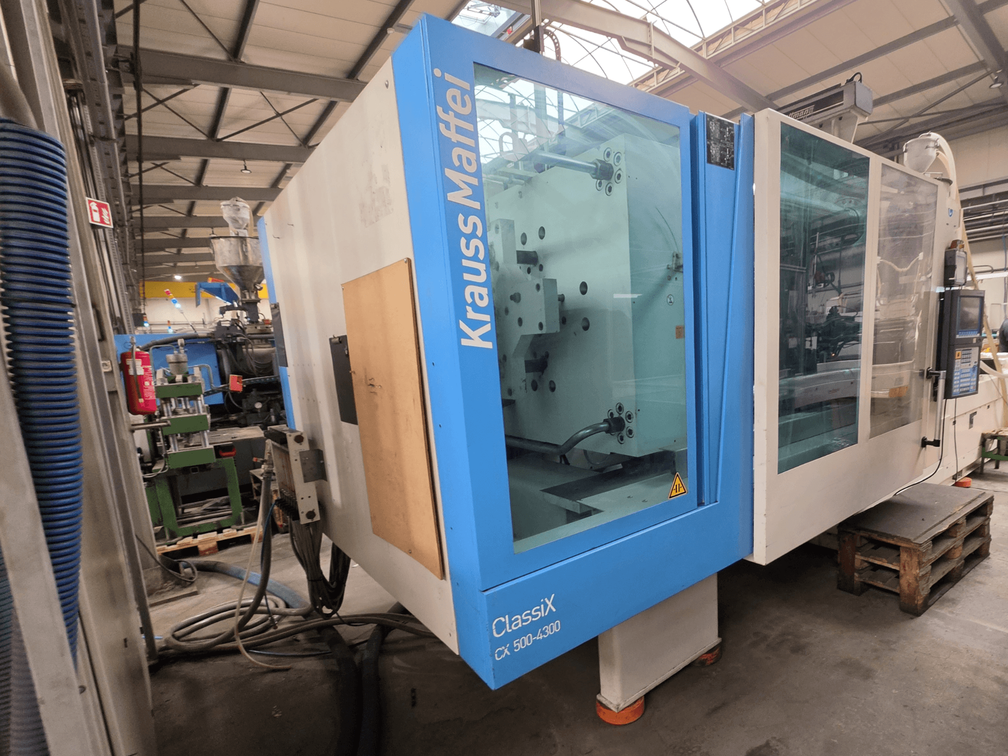 Krauss Maffei 500-4300 CX hidraulikus fröccsöntőgép, oldalnézet, a vezérlőpanel és a működtető alkatrészek bemutatása.
